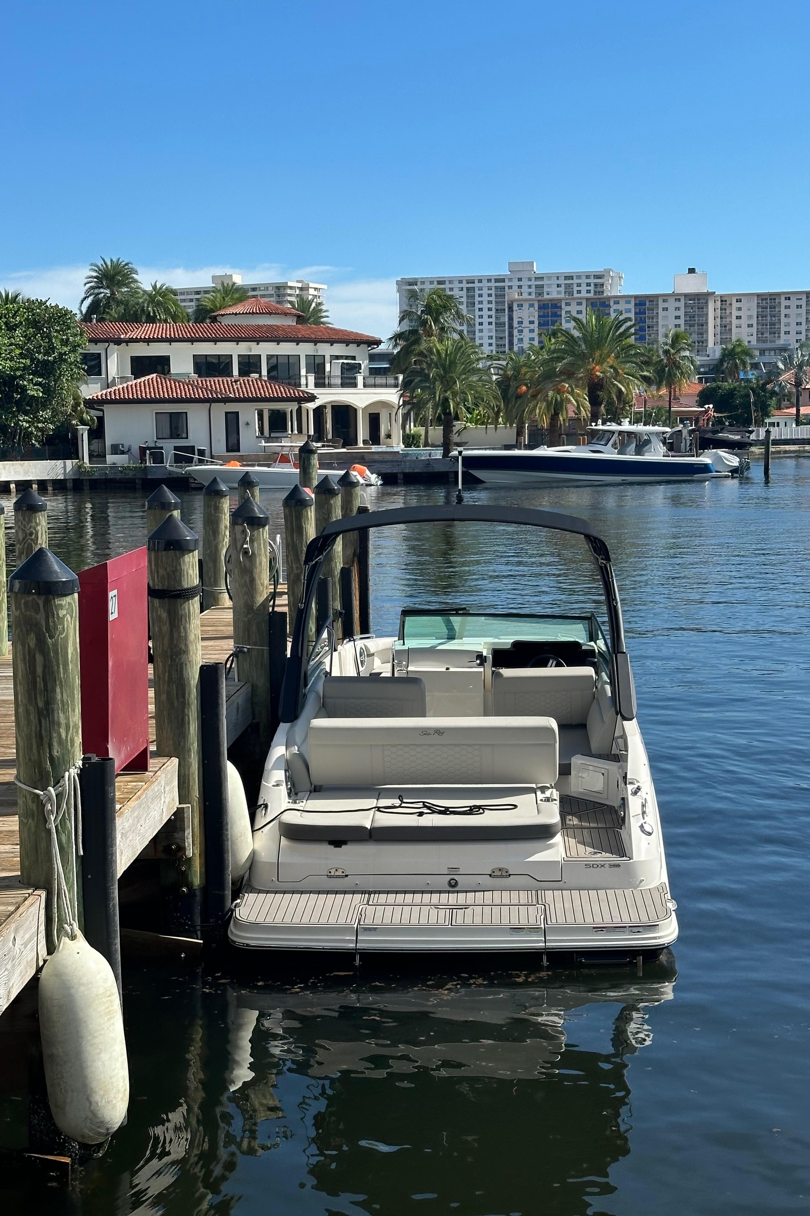2022 Sea Ray SDX 250 docked by waterfront homes and palm trees.