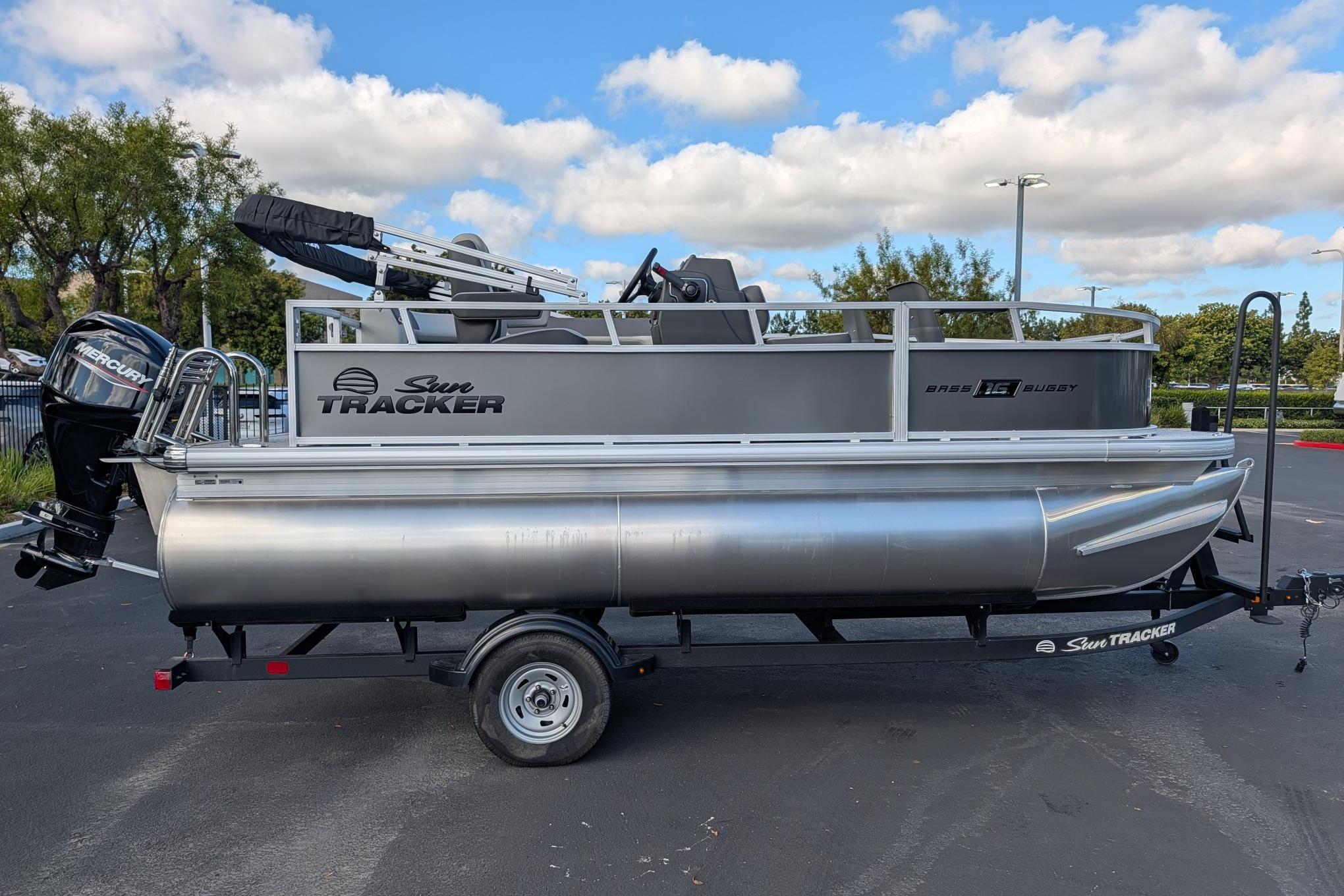 2026 Sun Tracker Bass Buggy 16 XL Select pontoon boat on trailer, parked outdoors.