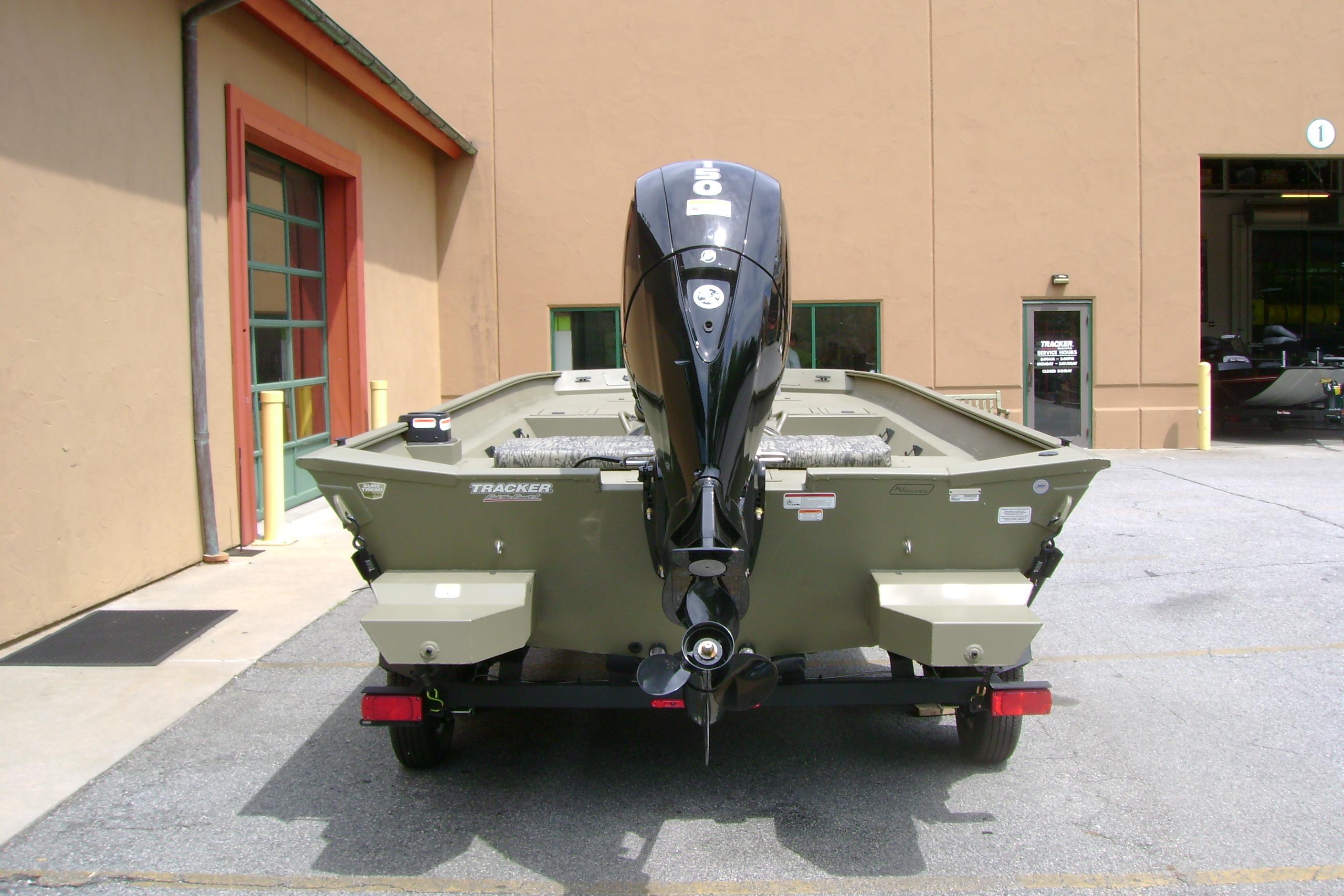 2026 Tracker Grizzly 2072 CC boat with outboard motor, parked outside a building.