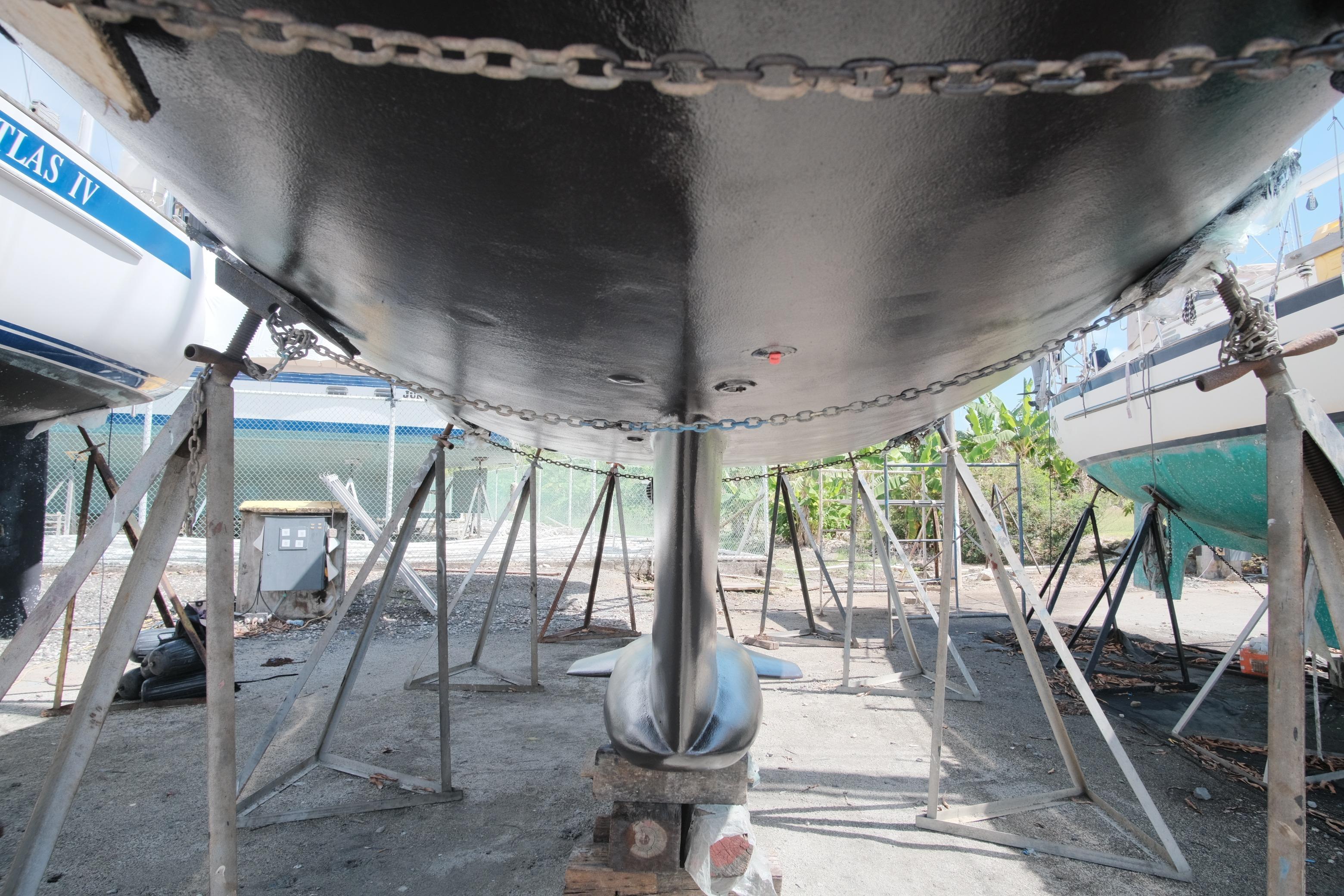 Underneath view of a 1996 Hunter 376 sailboat on stands in a boatyard.