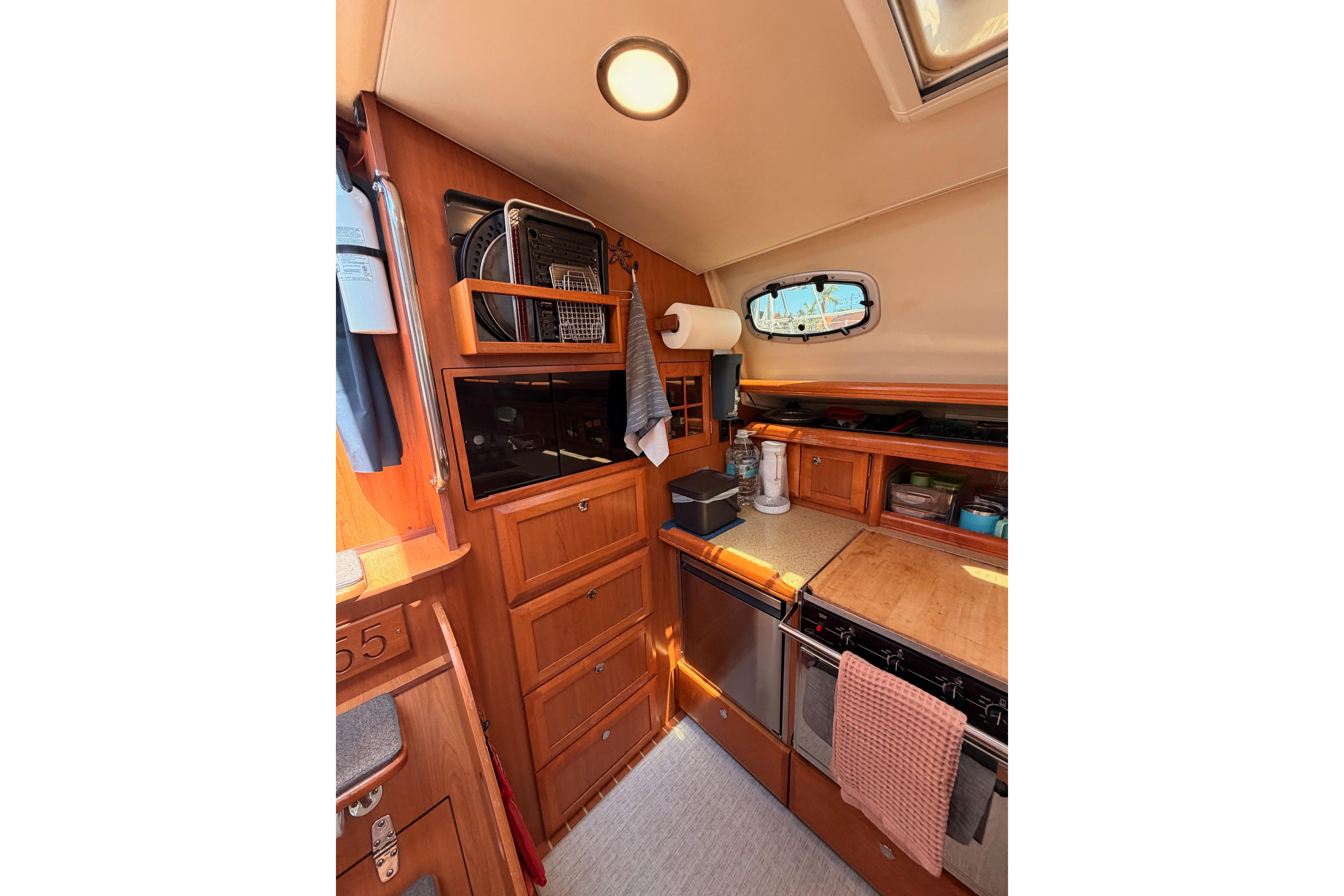 Interior of 2008 Hunter 45 Deck Salon yacht kitchen with wooden cabinetry and appliances.