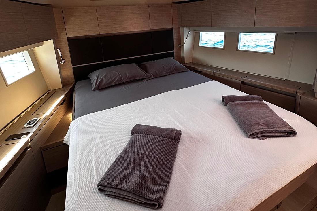 Luxurious 2024 Hanse 588 yacht cabin with elegant bedding and ocean view windows.