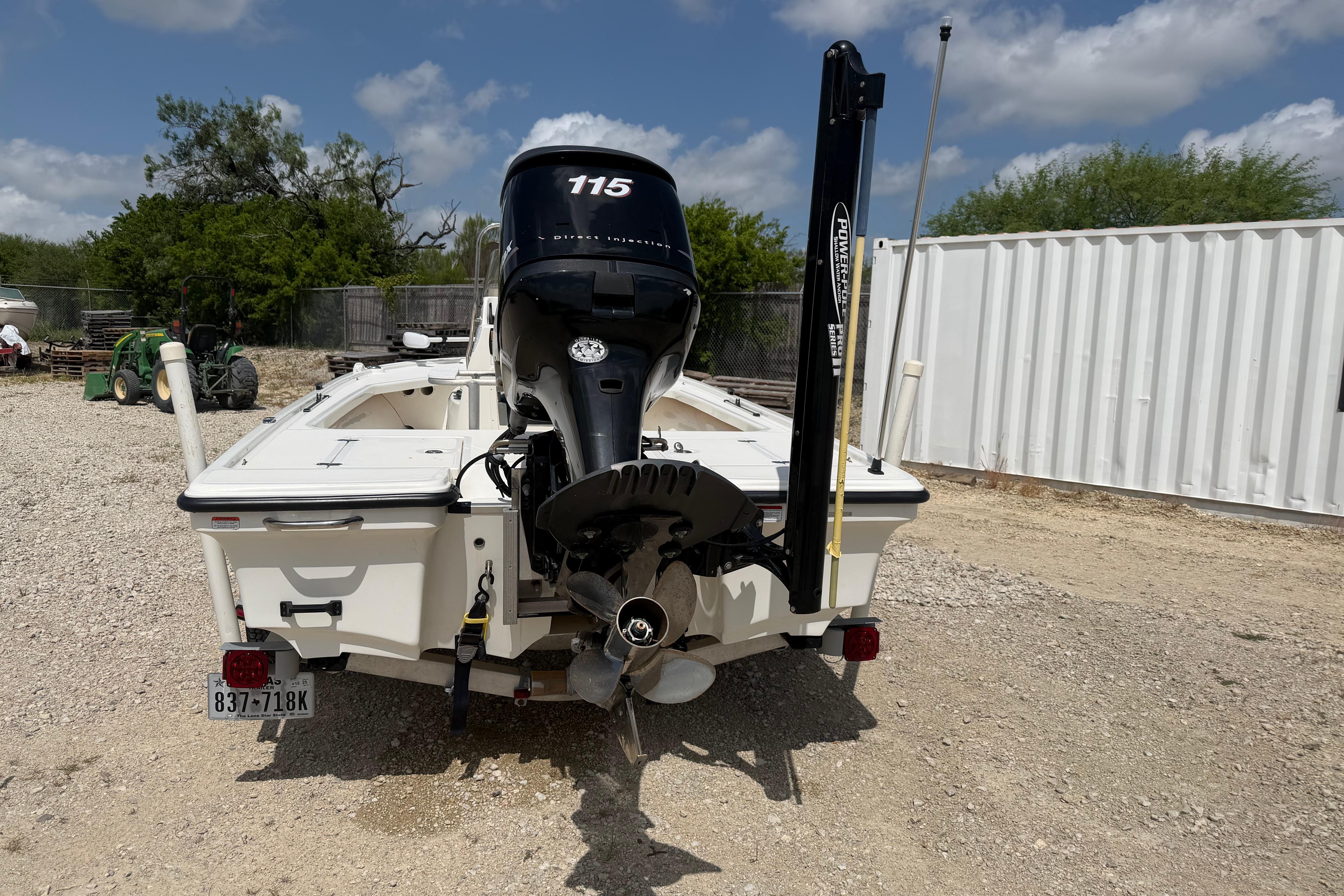 2012 Mako 18 LTS boat with outboard motor, parked on gravel, under a partly cloudy sky.