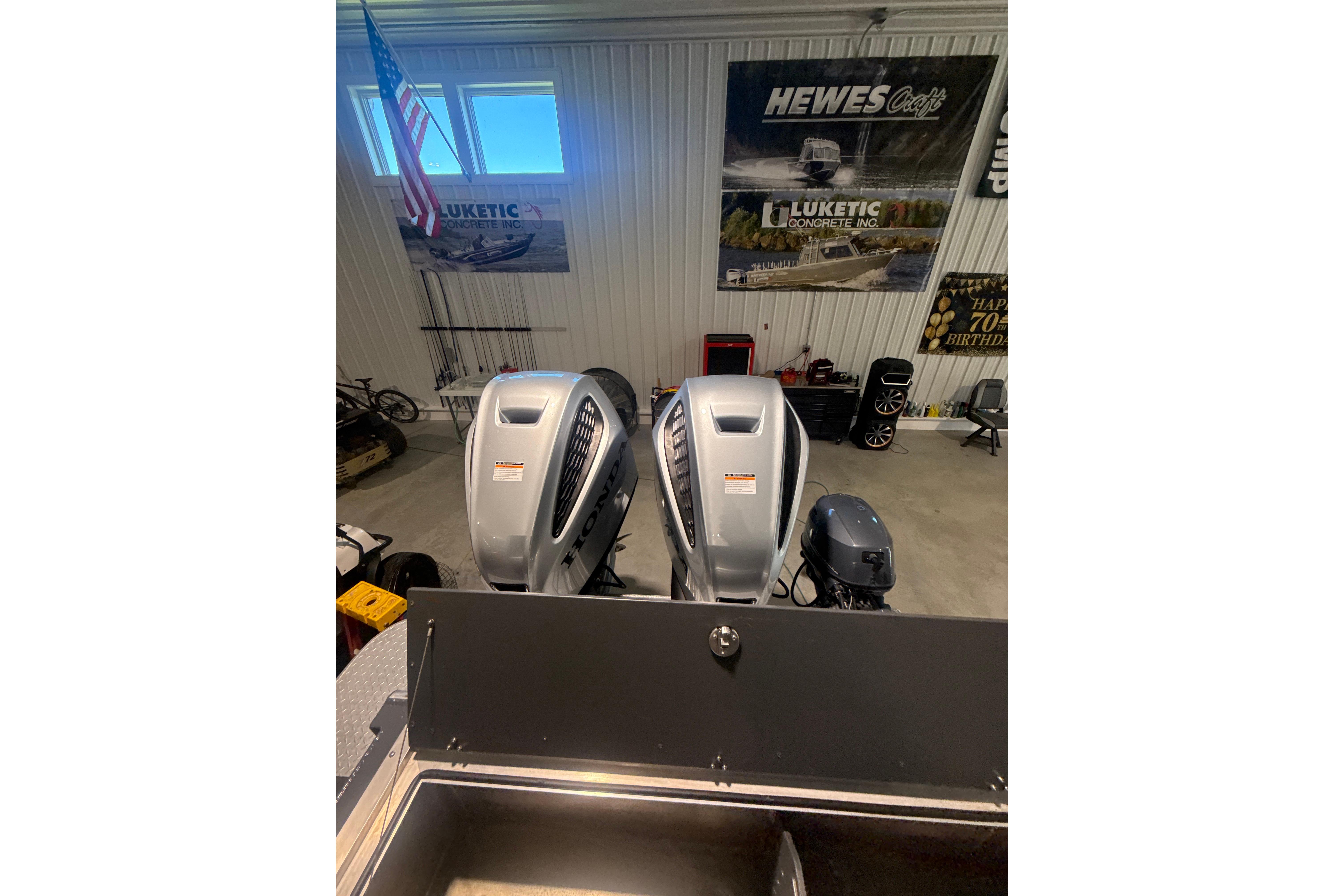 2022 Hewescraft 270 Alaskan Hardtop with dual outboard motors in a showroom.