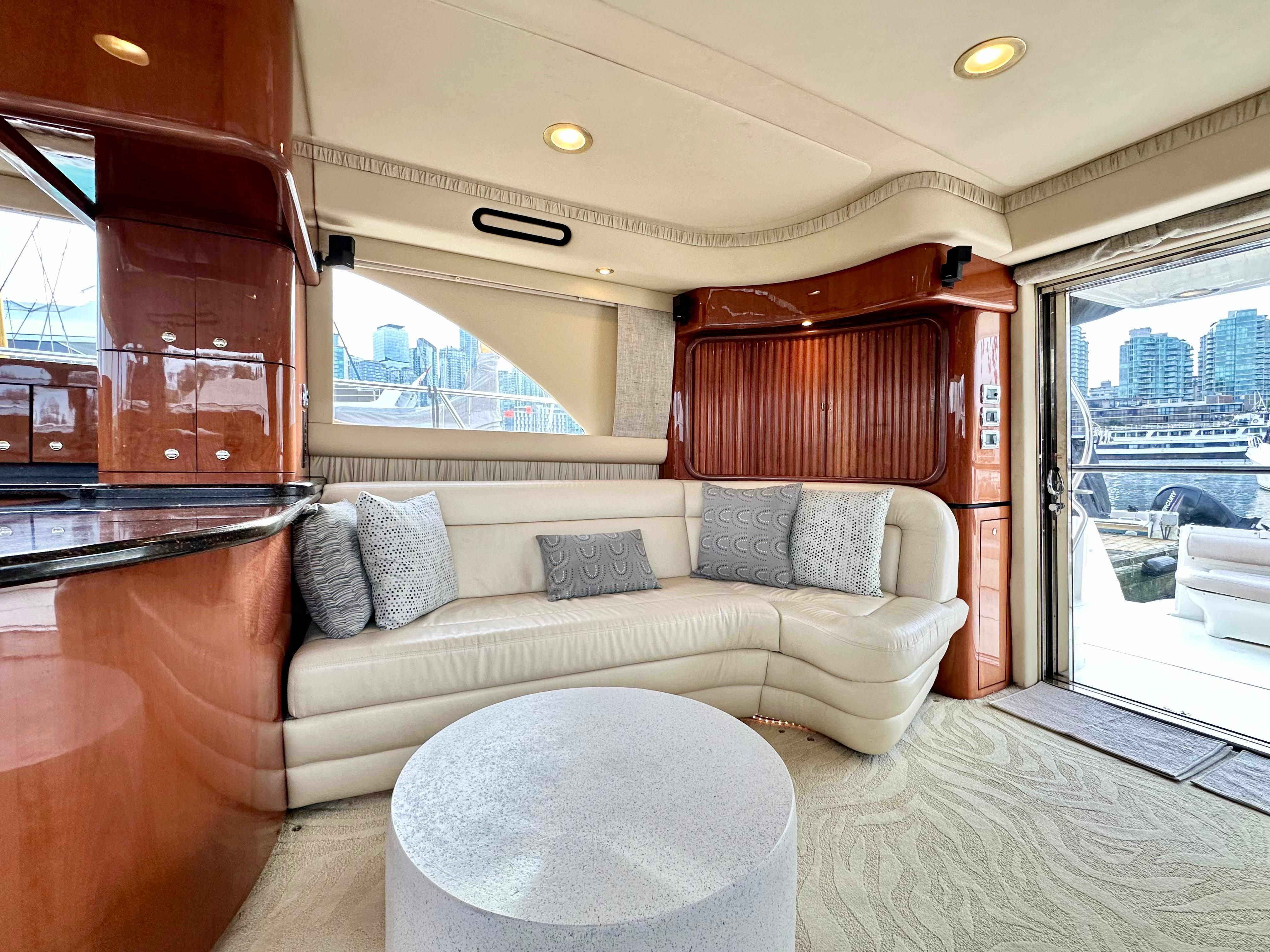 Luxurious interior of 2002 Sea Ray 560 Sedan Bridge yacht with plush seating and city view.