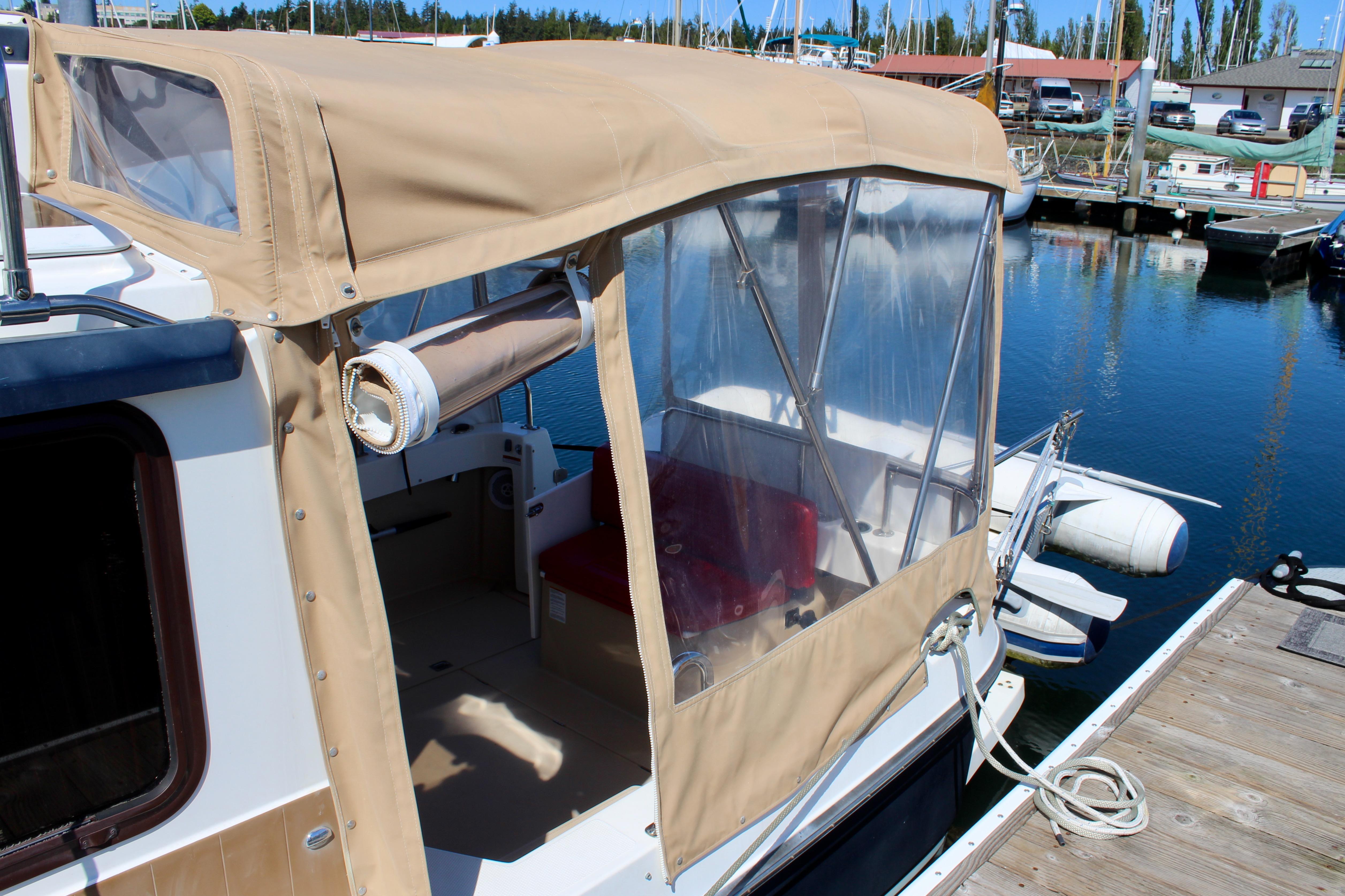 2011 Ranger Tugs R-27 boat with tan canopy docked at marina.