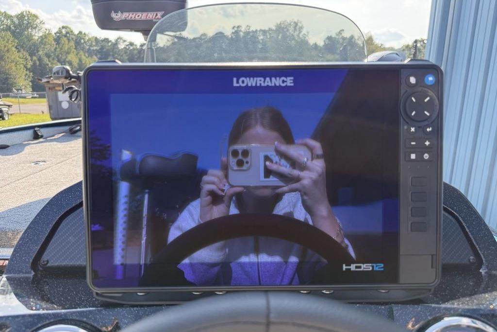 Dashboard of 2026 Phoenix 20 XE with Lowrance HDS12 display reflecting a person taking a photo.