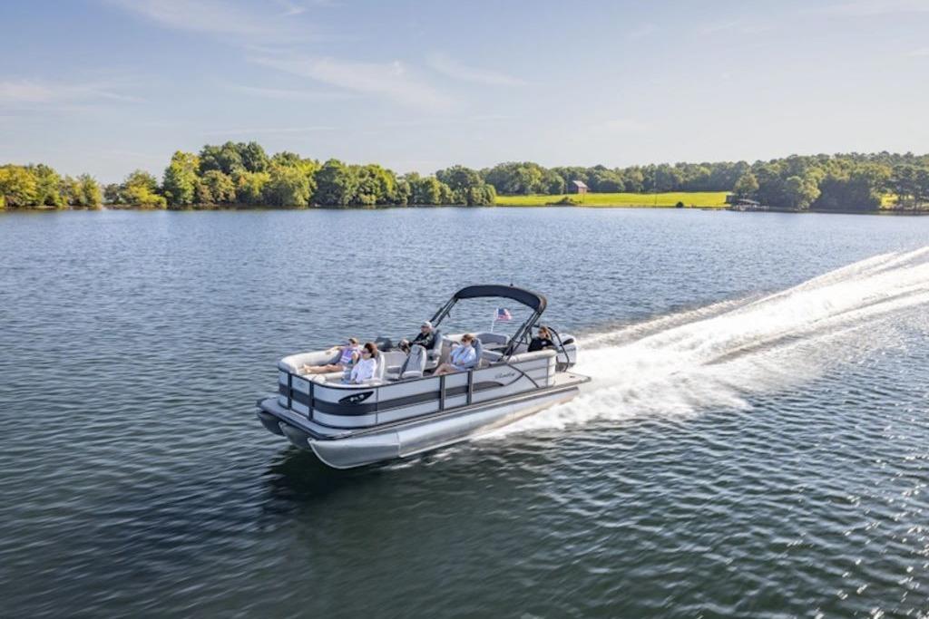 2026 Bentley Pontoons Legacy 223 Cruise on a serene lake, surrounded by lush greenery.
