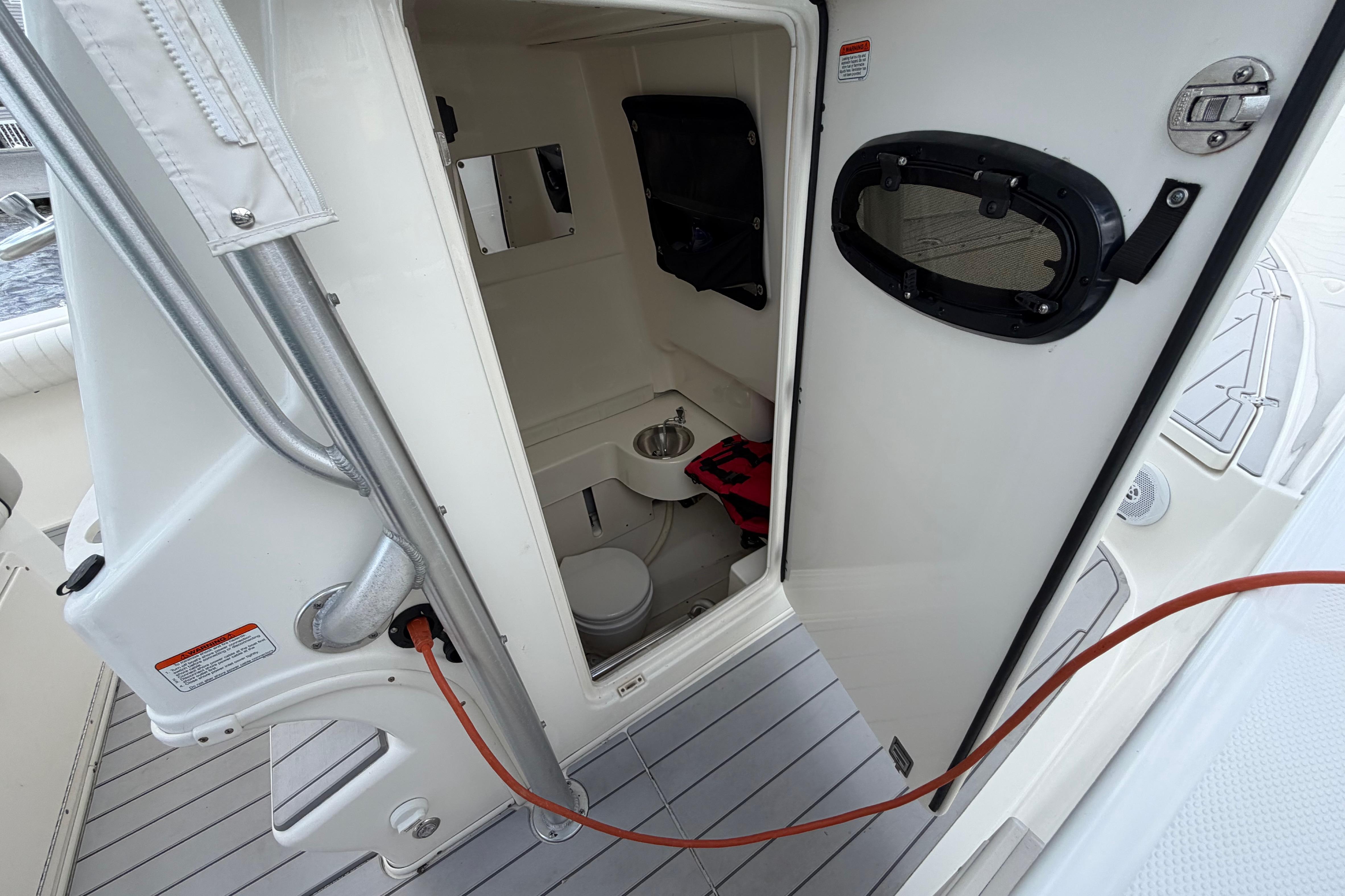 2017 Mako 284 Center Console boat interior with open door, showcasing compact restroom facilities.