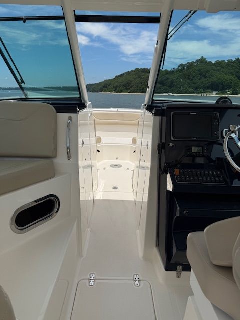 The boat features an open console with views of the water and a wooded shoreline.