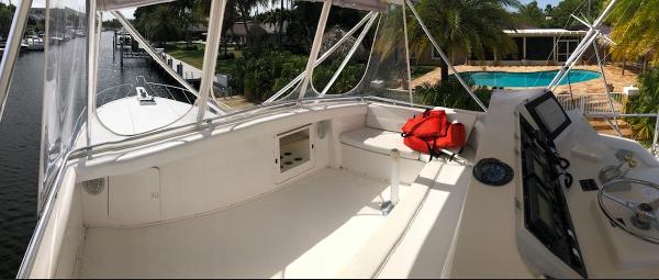 1997 Bertram Convertible yacht deck with navigation controls and life jackets, docked near a pool.