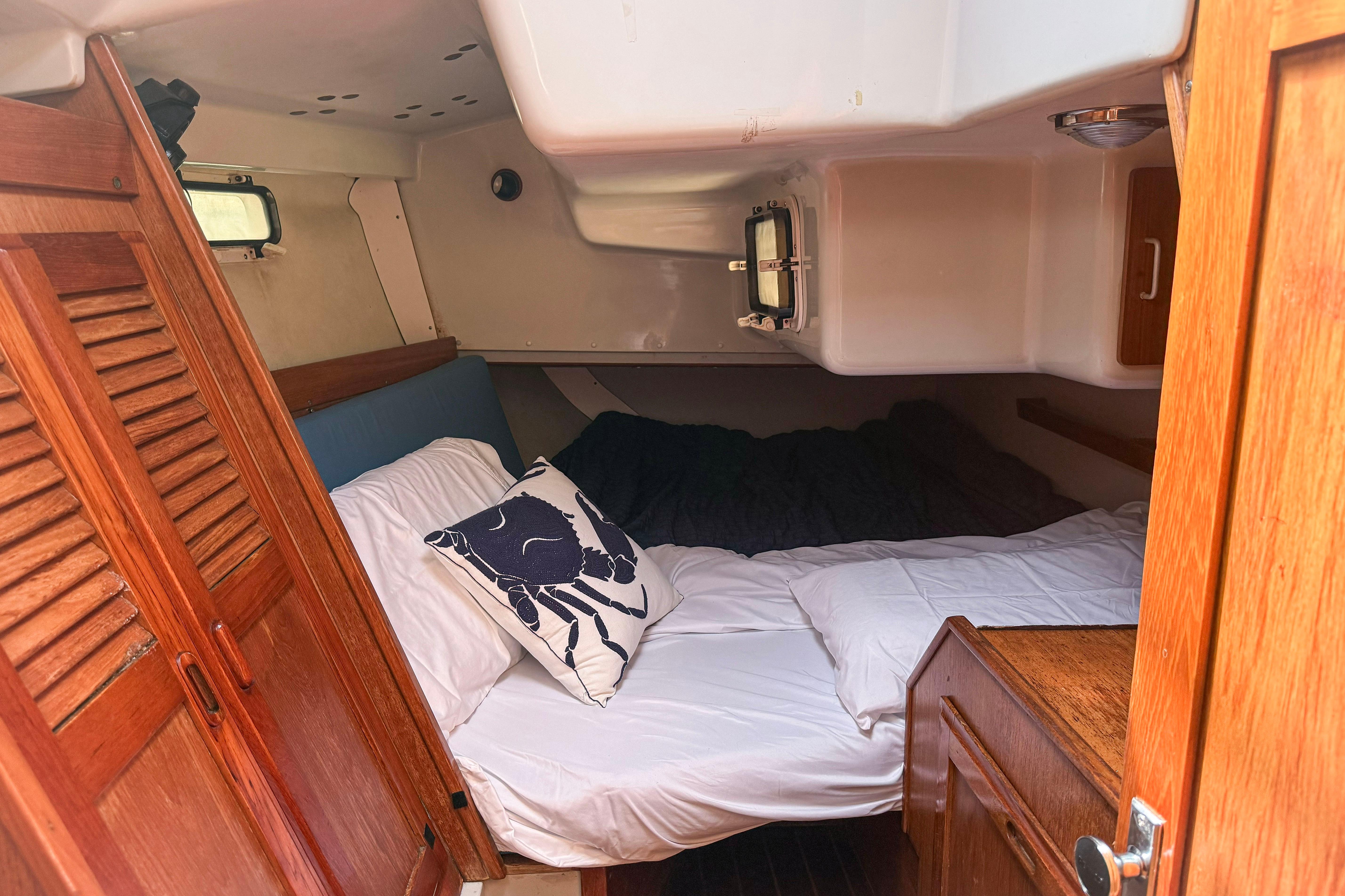 Cozy cabin interior of a 1988 Oday 40 sailboat with wooden accents and bedding.