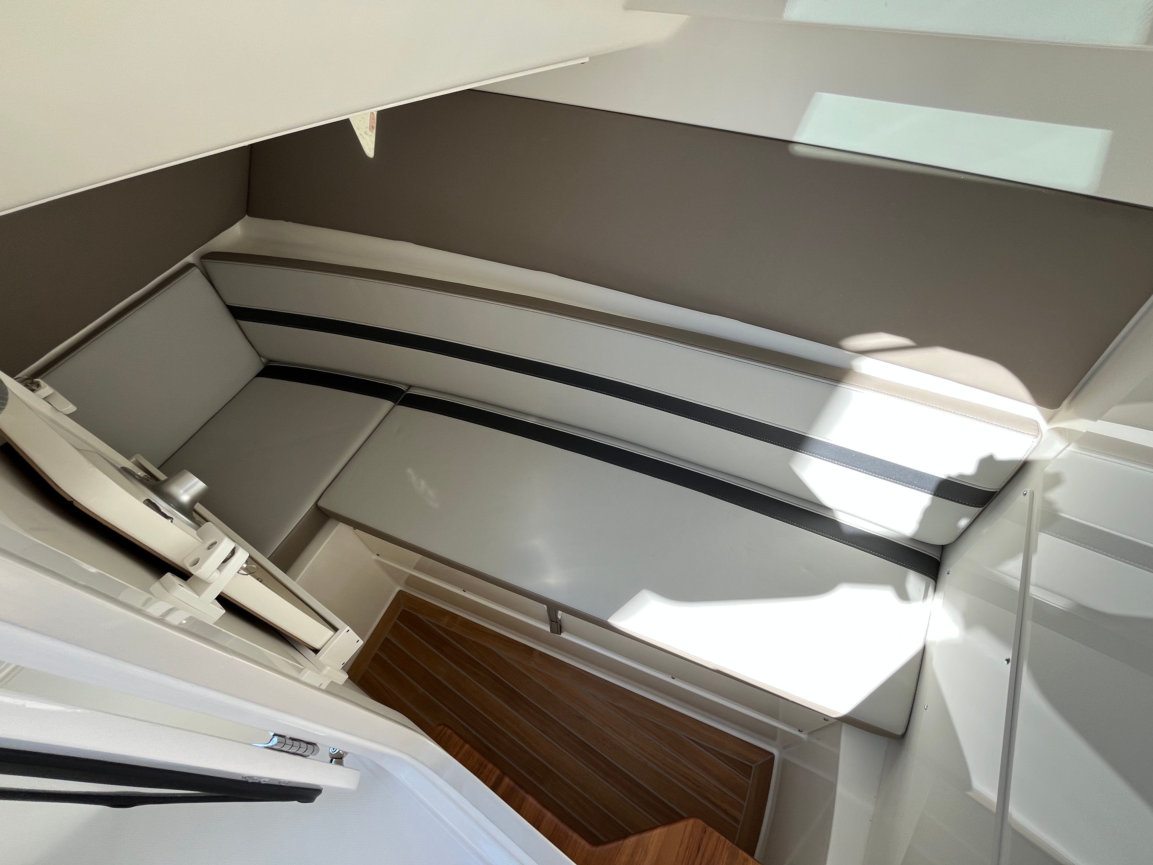 Interior of a modern cabin with cushioned benches and wooden flooring.