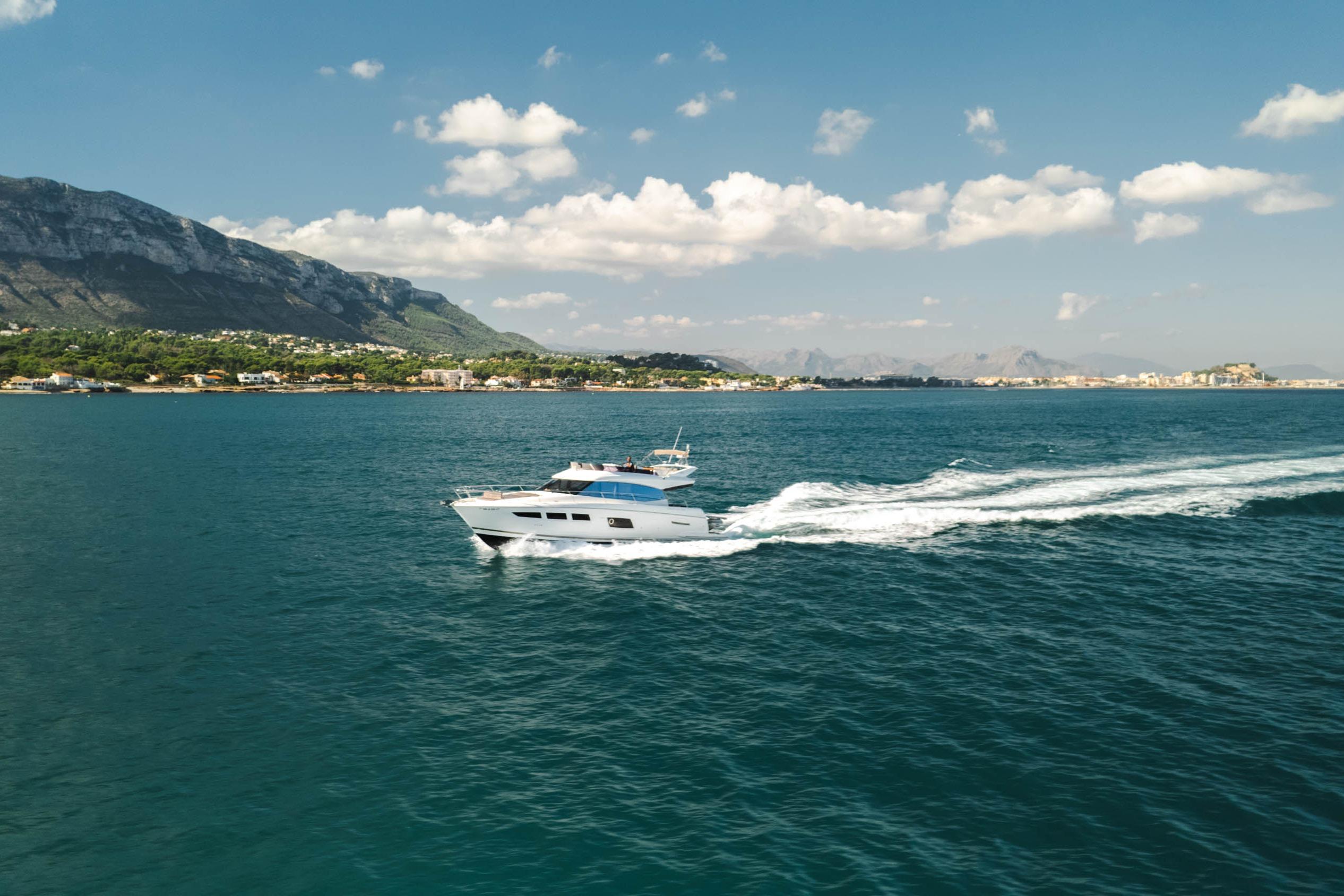 2017 Prestige 560 yacht cruising on blue ocean near scenic coastline.