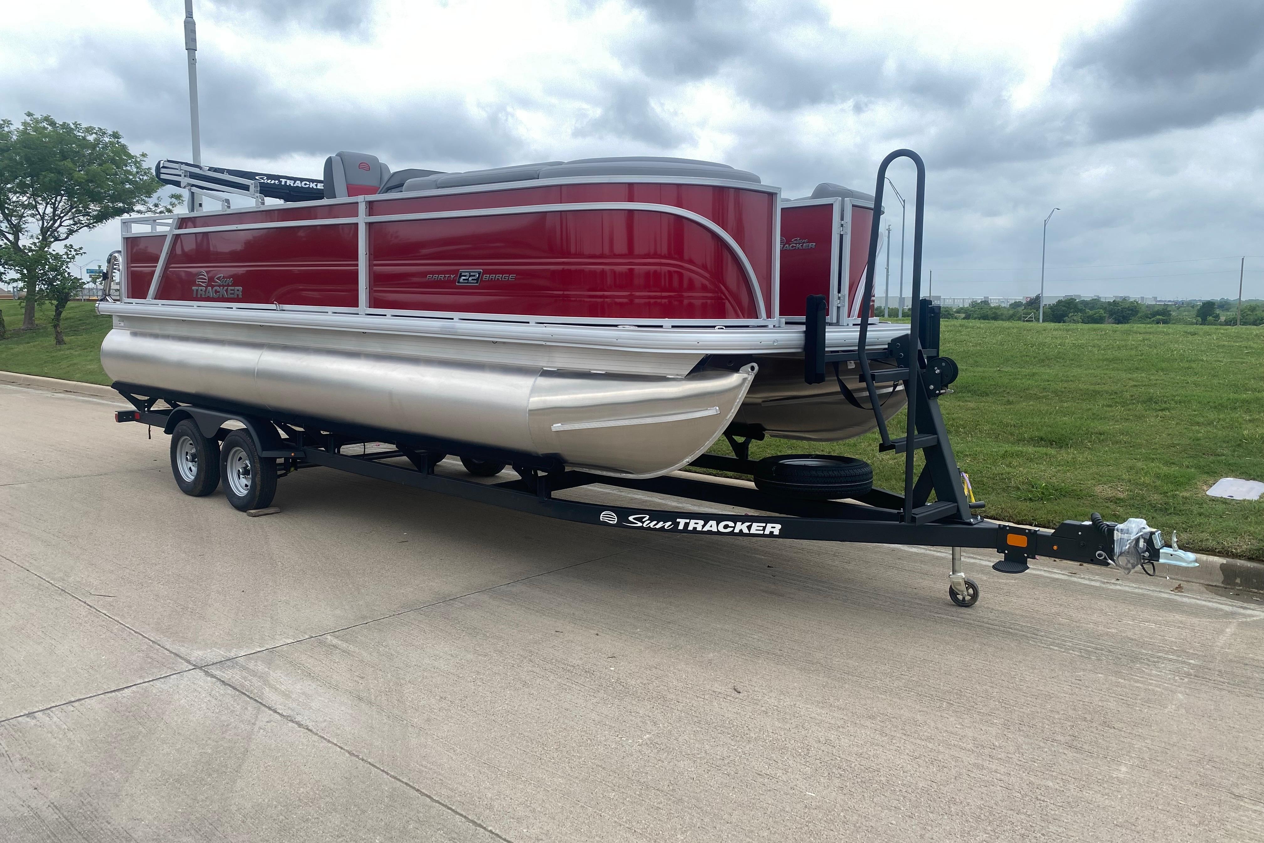 2026 Sun Tracker Party Barge 22 RF DLX pontoon boat on trailer, parked on road.