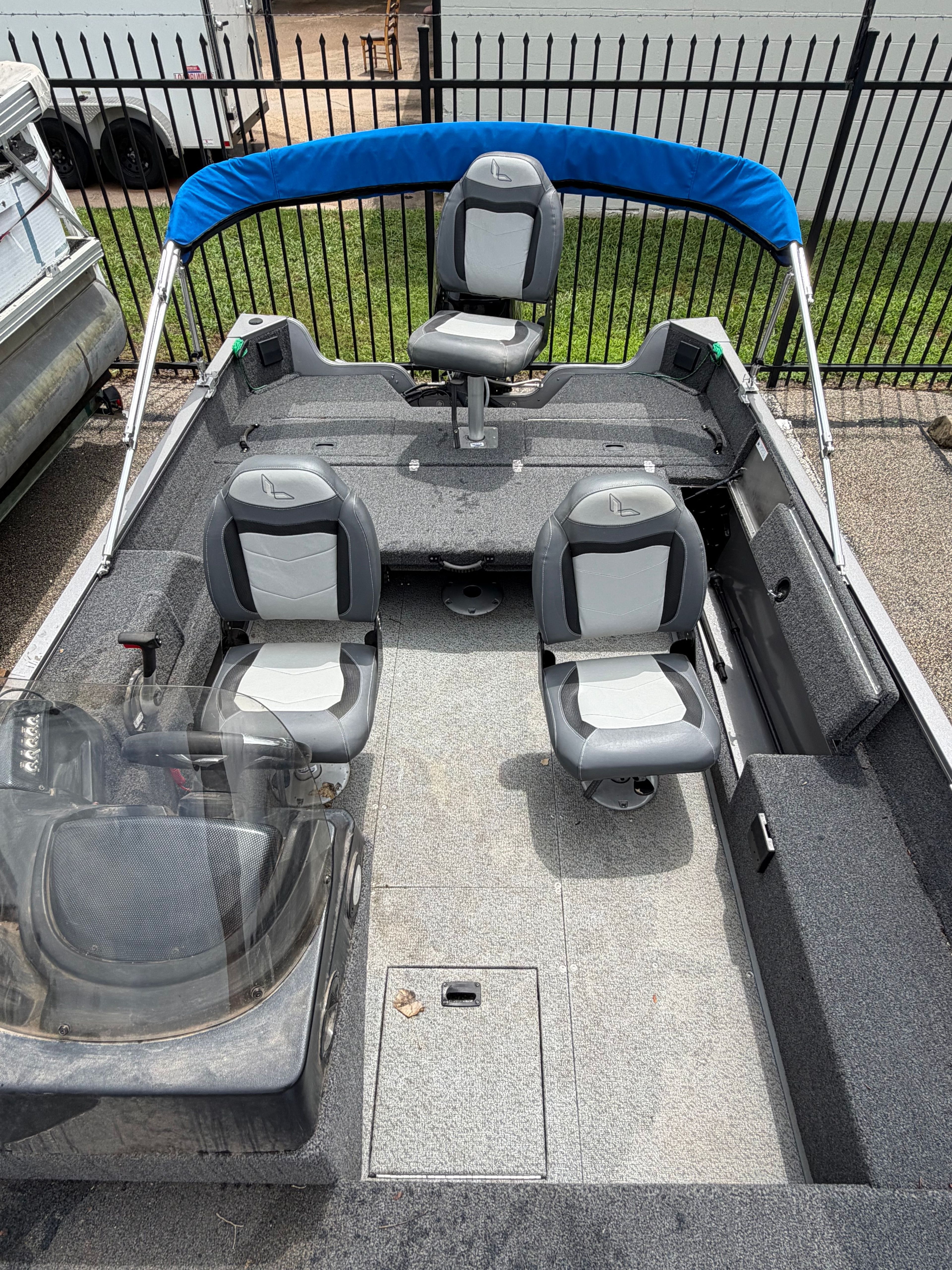 The image shows a 2023 Lowe Fishing Machine 1675SC boat with gray seats and a blue canopy.