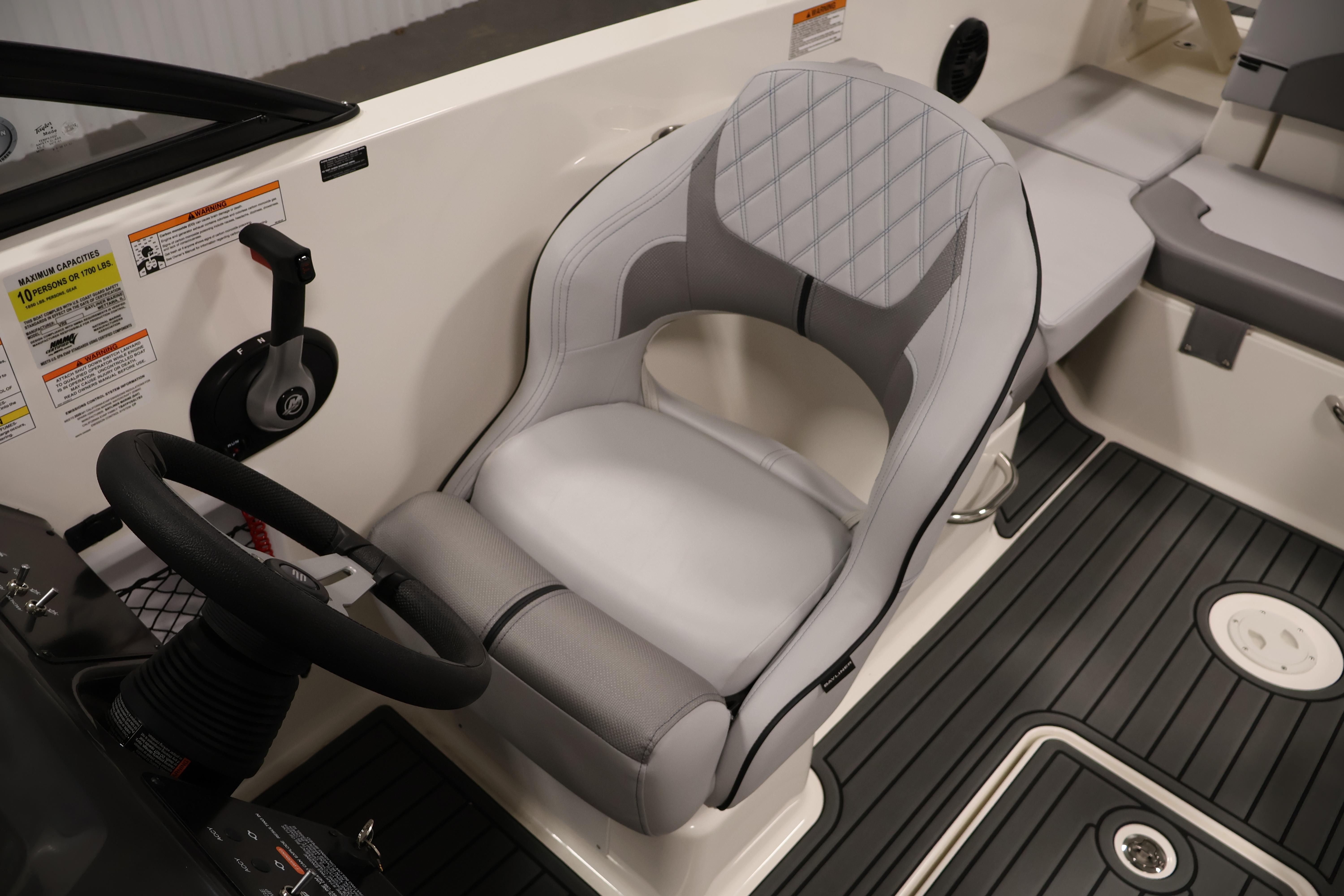2026 Bayliner VR6 Bowrider I/O cockpit with steering wheel and cushioned seat.