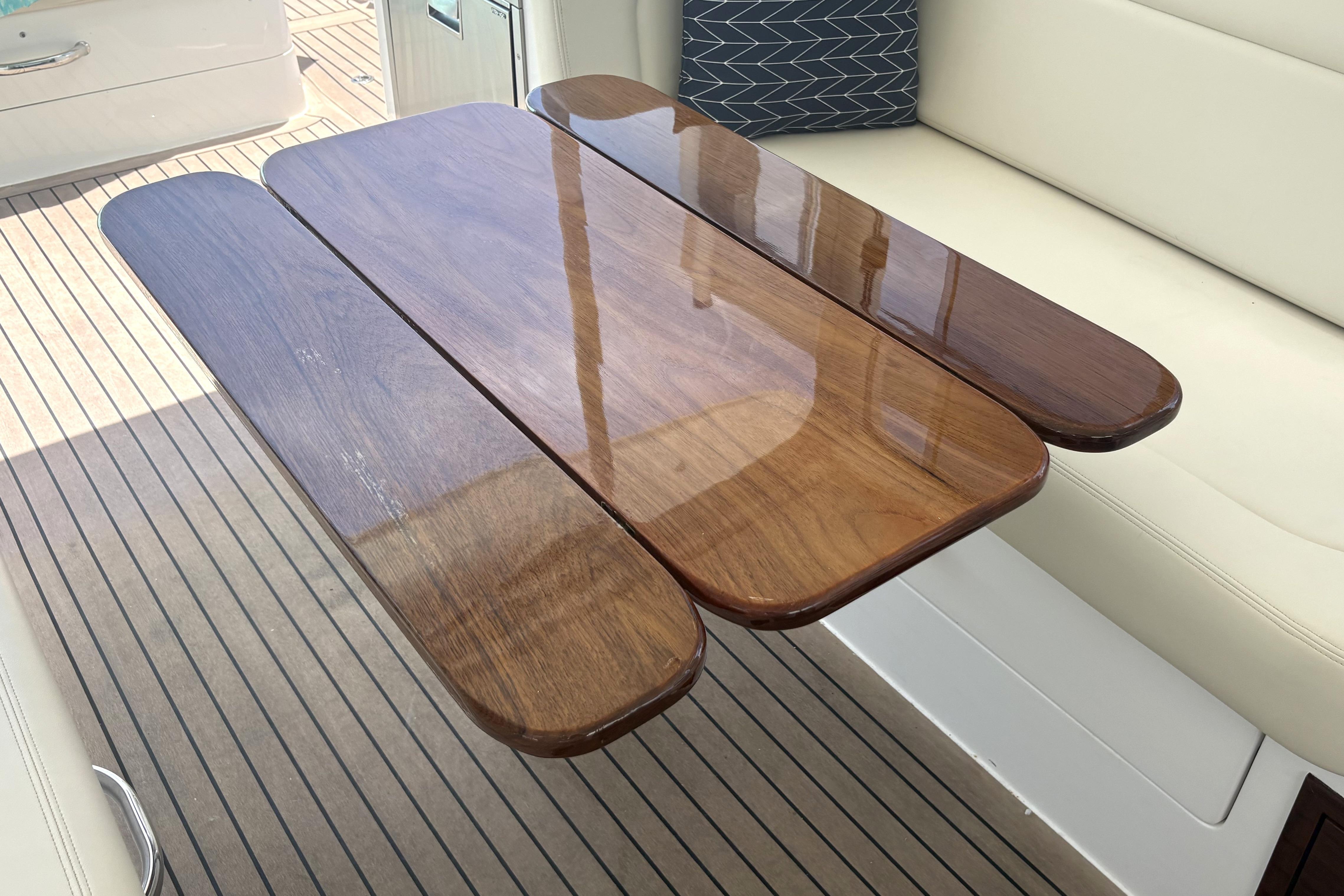 Polished wooden table on 2024 MJM 35z yacht with cushioned seating.