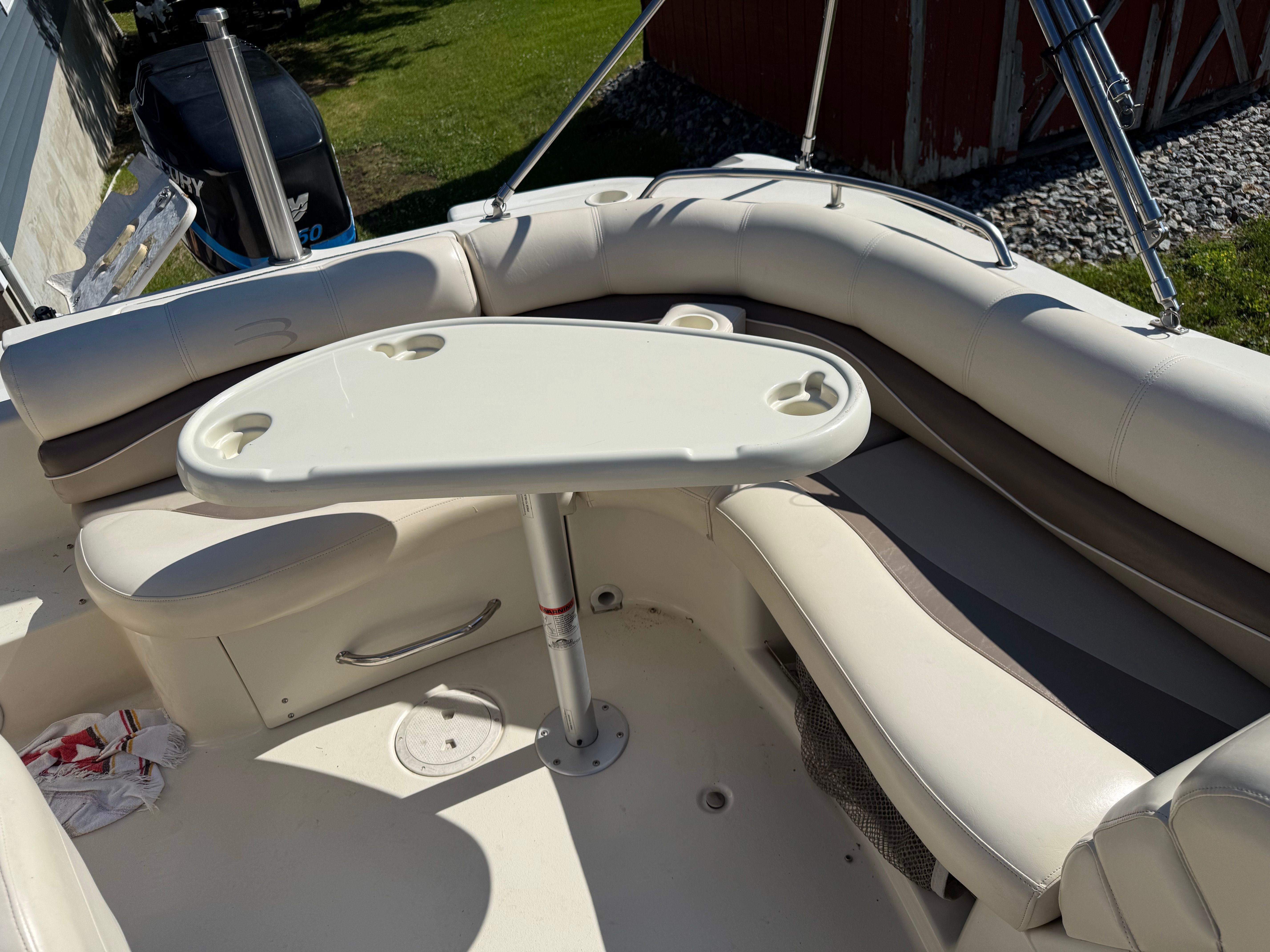 A sleek boat with beige seating area and a white table.