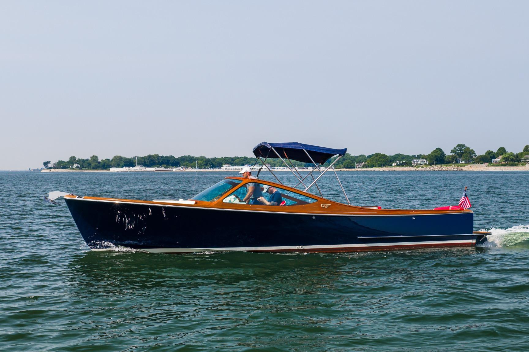 2005 Hinckley Talaria 29R cruising on open water with scenic shoreline in background.