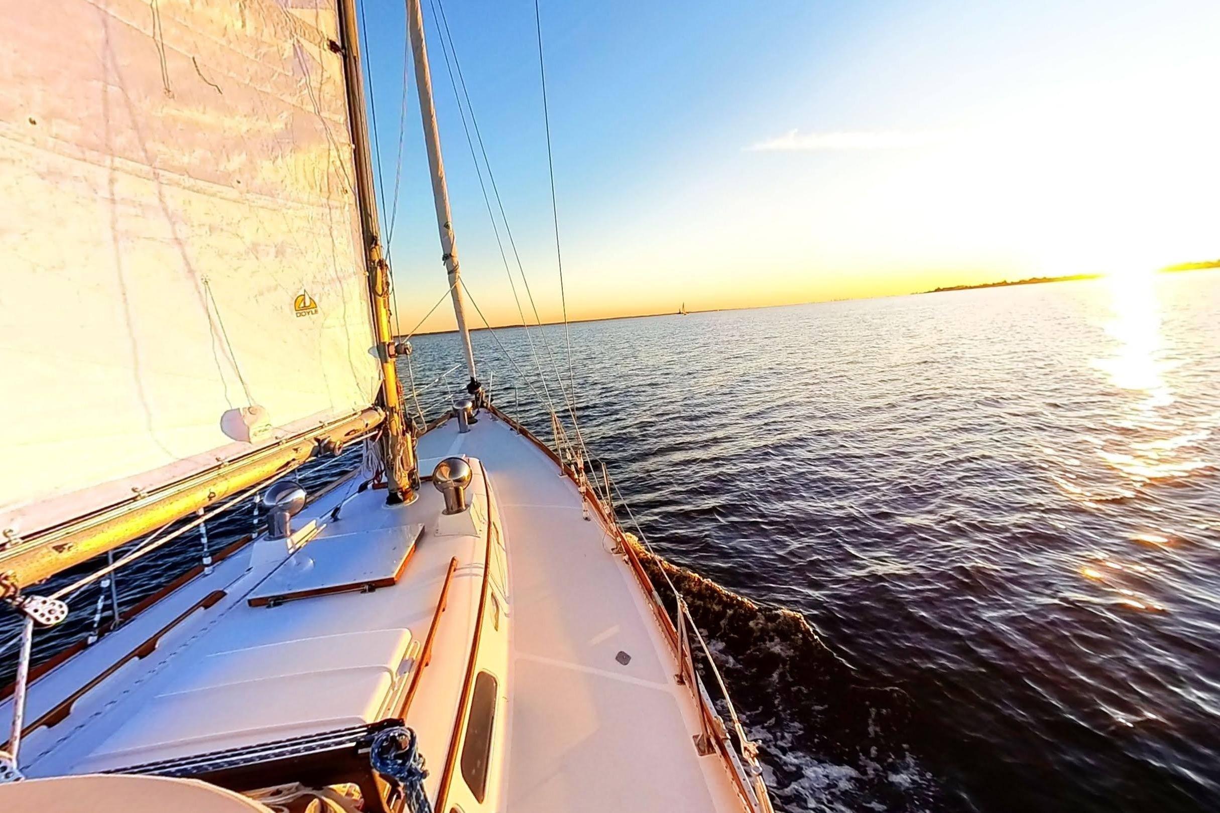 Sailing on a 1970 Hinckley Bermuda 40 yacht at sunset over calm waters.