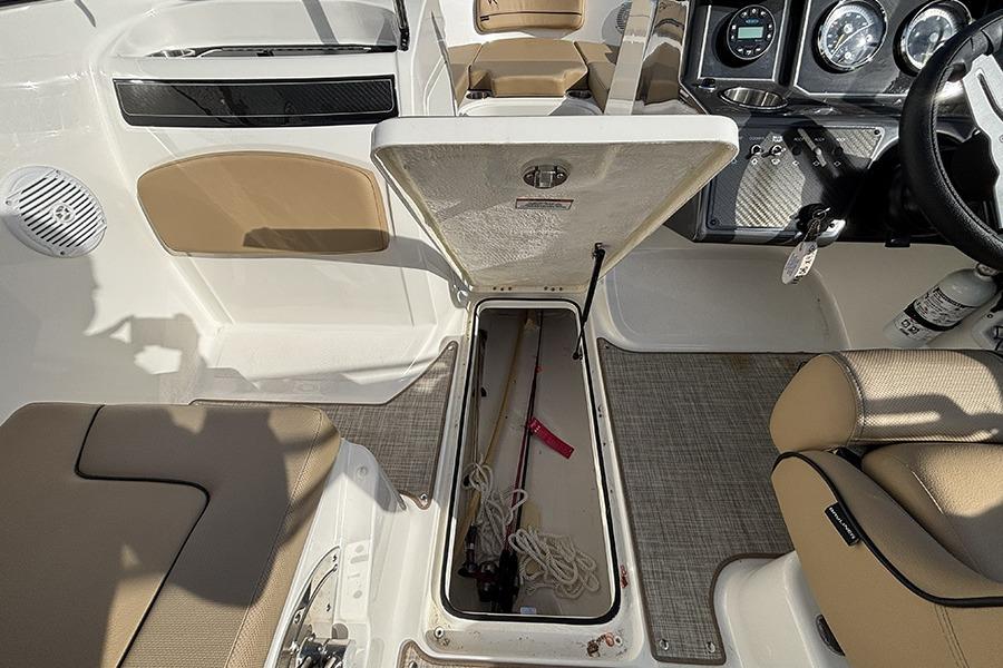 2023 Bayliner VR5 Bowrider OB interior with open storage compartment and fishing gear.