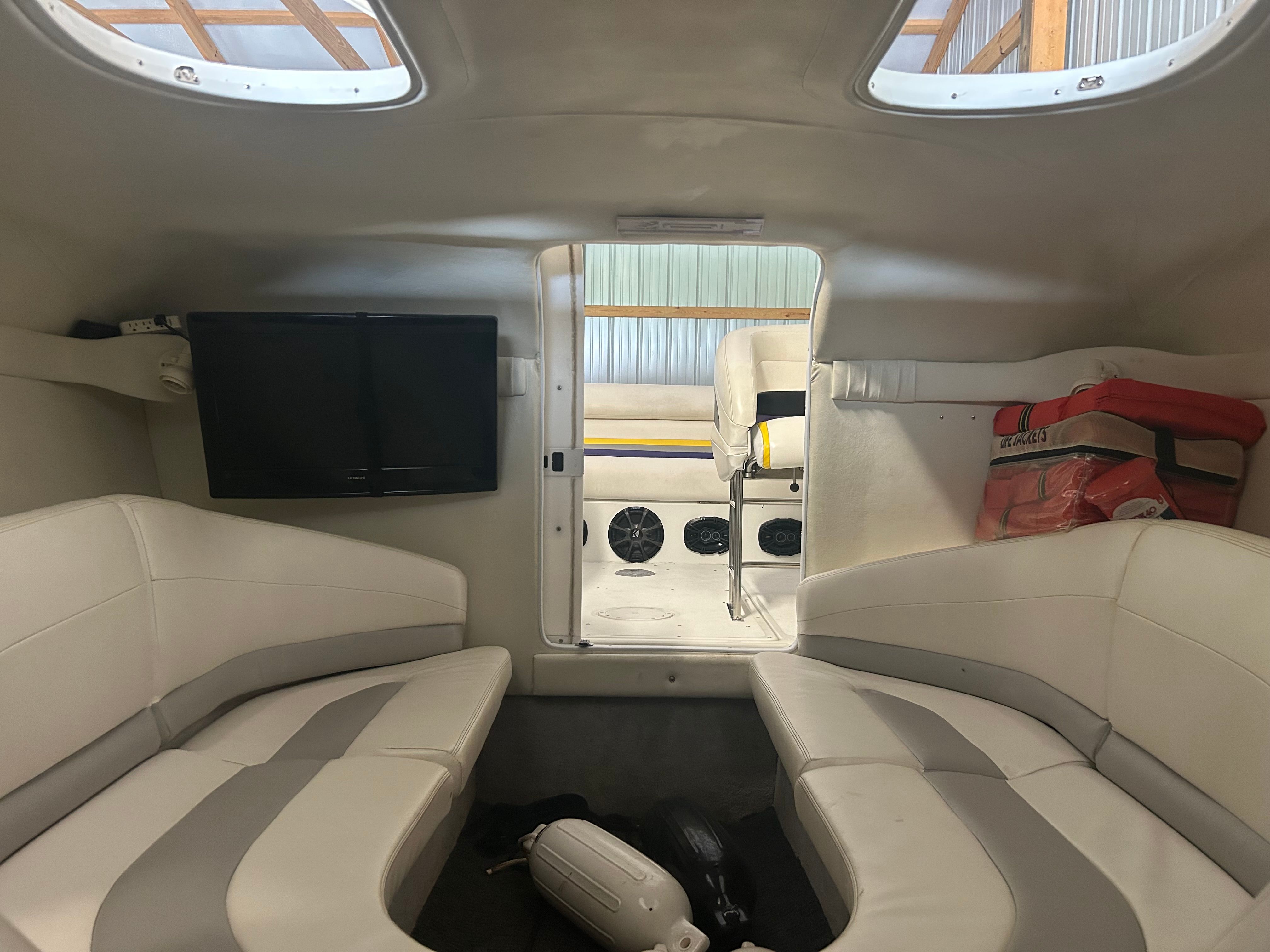 Interior of a 1996 Baja 302 with gray and white seating and a television.