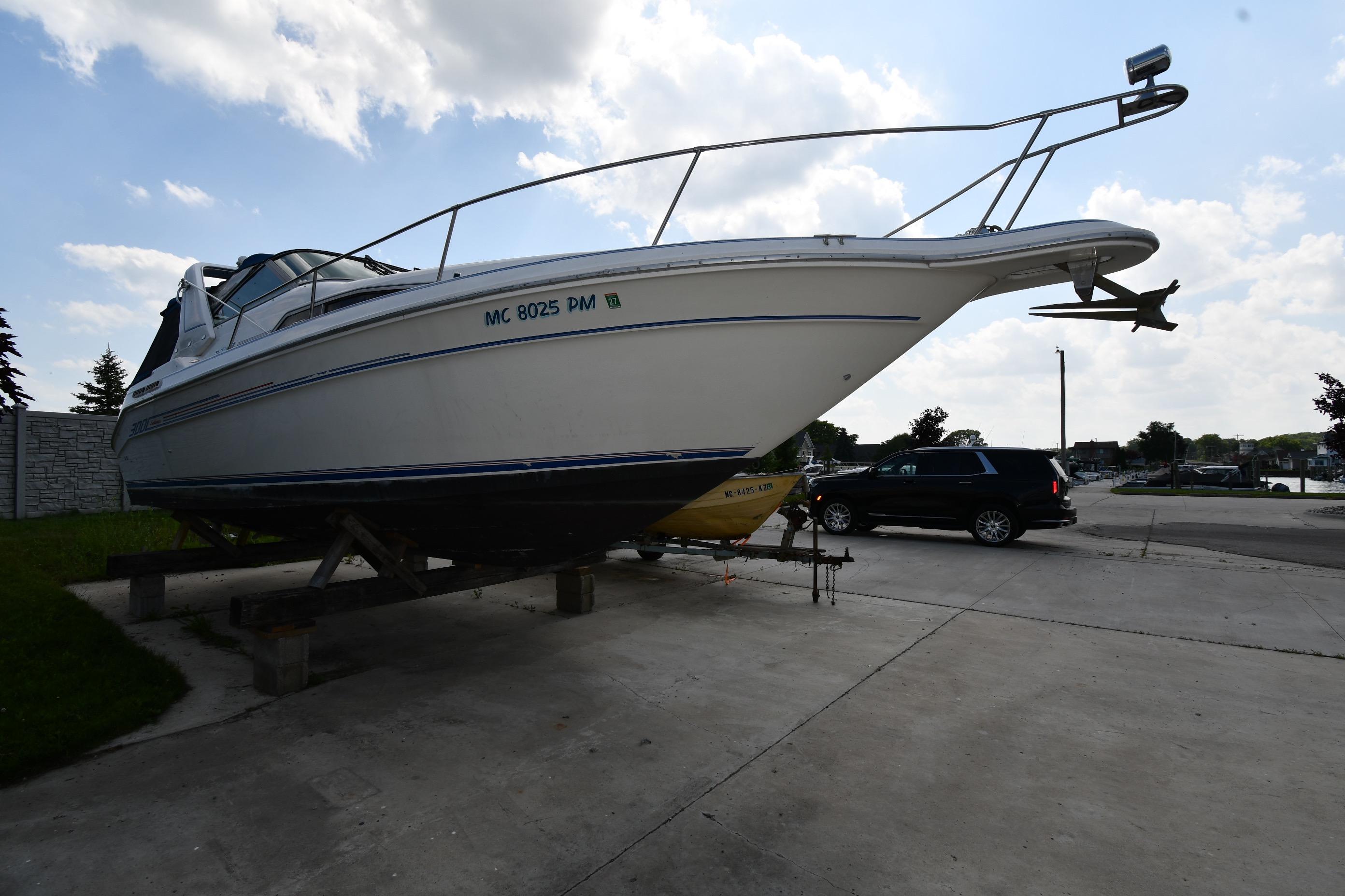 1993 Sea Ray 300 Sundancer boat on trailer, parked outdoors under a partly cloudy sky.