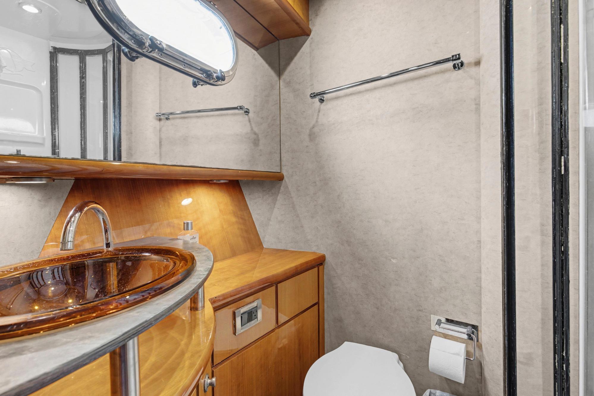 Luxurious bathroom in 2004 Queenship 76 Baretta yacht with elegant wood finishes.