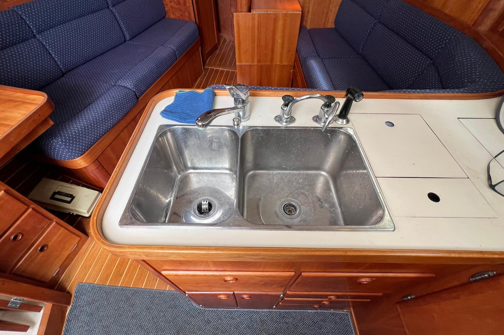 Galley sink in 1998 Sabre 362 yacht with wooden cabinetry and blue upholstered seating.