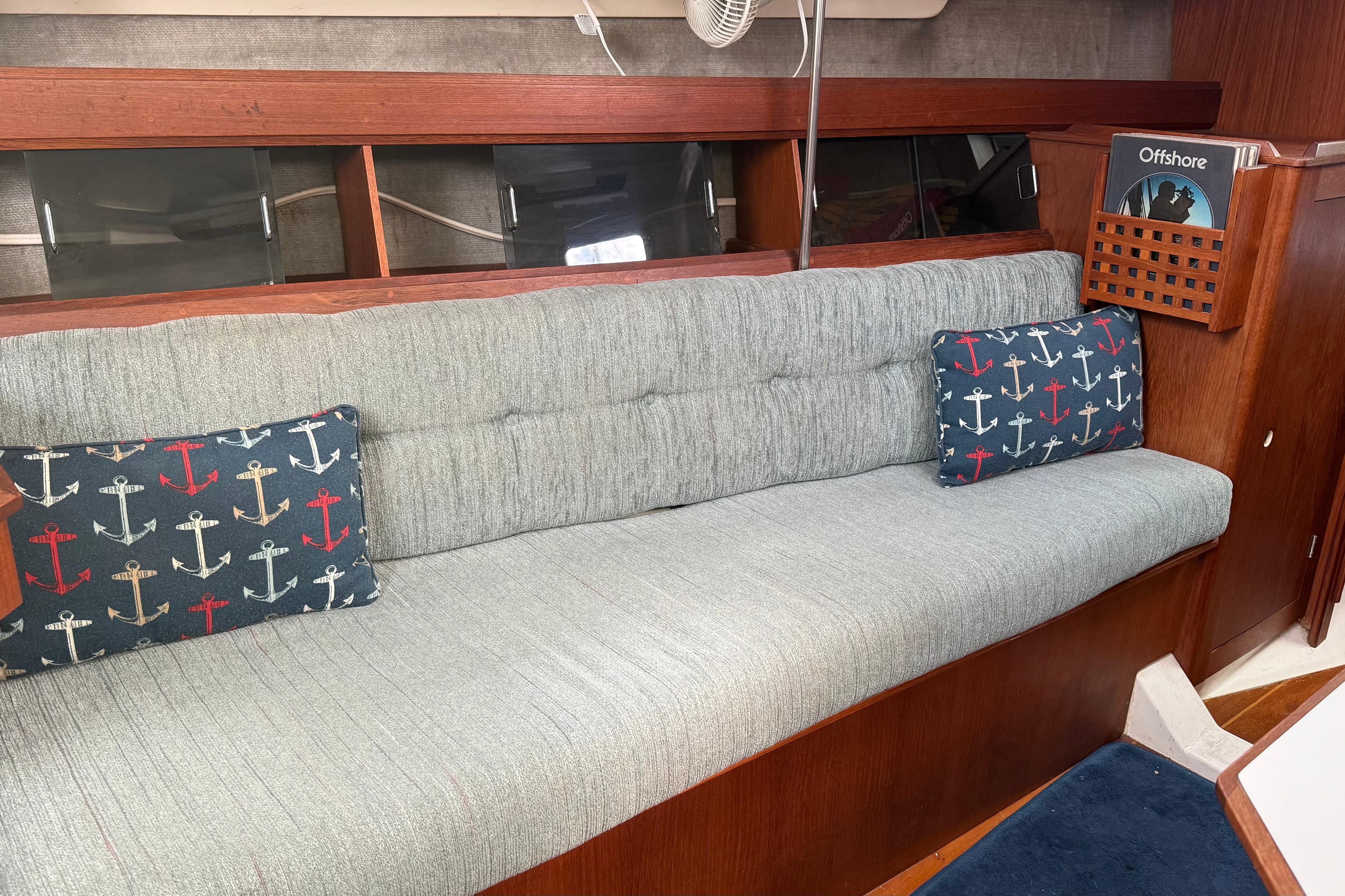 Interior of 1984 Hunter 31 sailboat with cushioned seating and nautical-themed pillows.