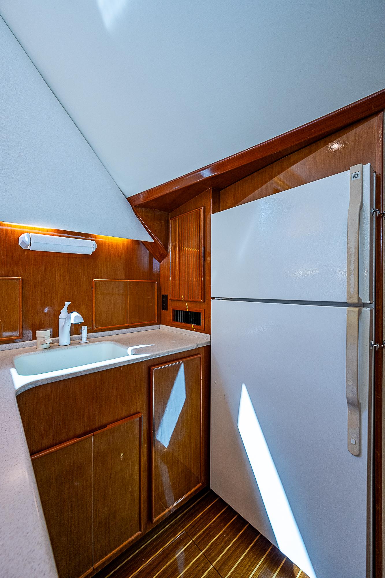 1999 Post 50 Convertible yacht kitchen with wooden cabinets and white appliances.