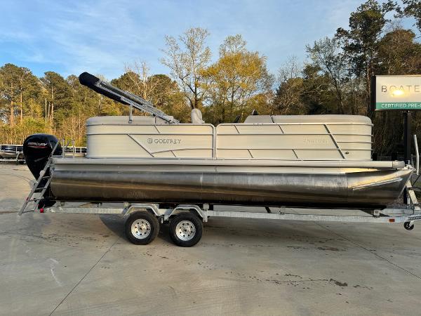 2022 Godfrey 2286 pontoon boat on trailer, parked outdoors with trees in background.
