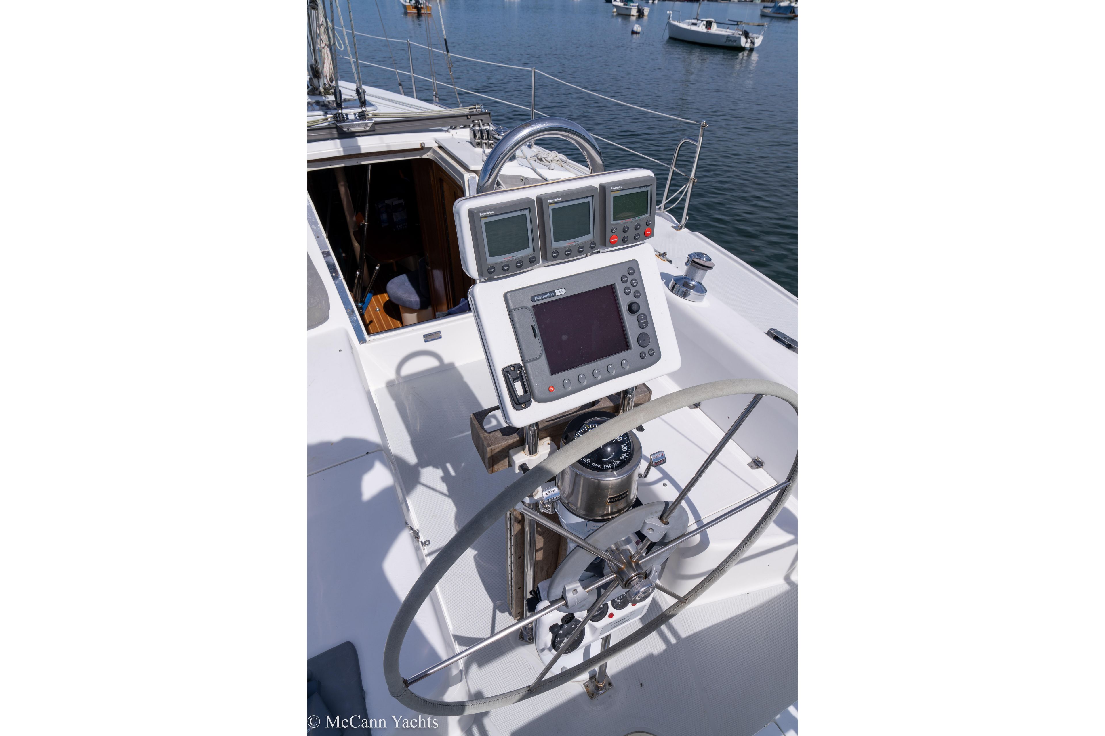 Steering wheel and navigation equipment on 2003 Catalina 320 yacht, docked in marina.