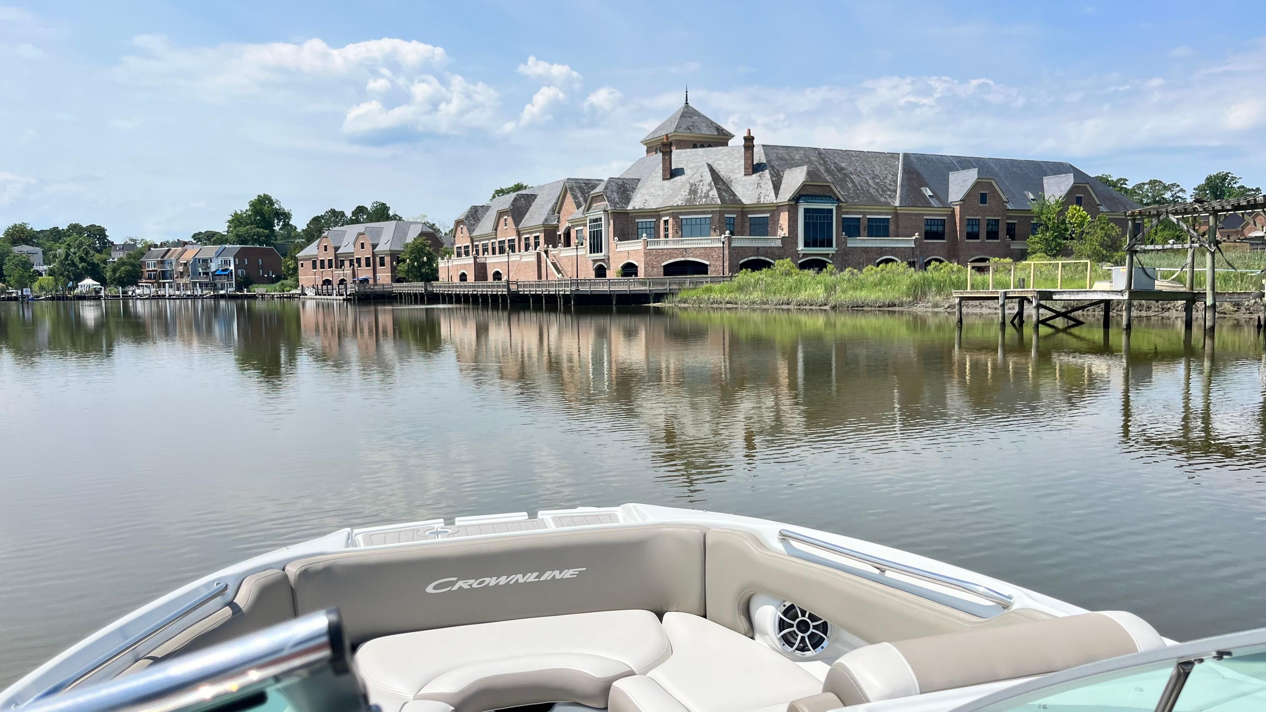 Crownline E 285 2019 on calm water with a scenic waterfront backdrop.