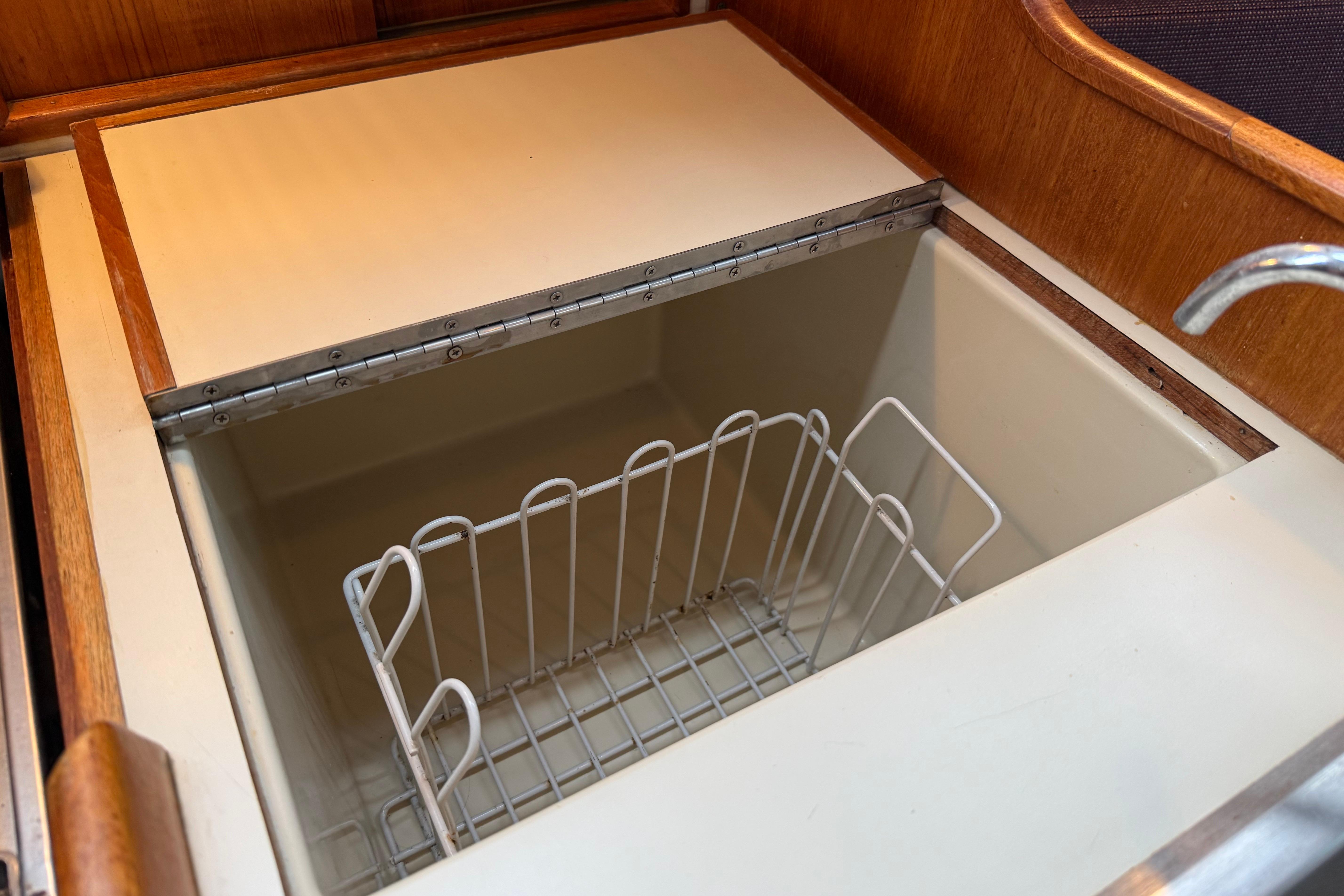 Built-in storage compartment on 1988 Ericson 32-200 sailboat, featuring a wire basket.