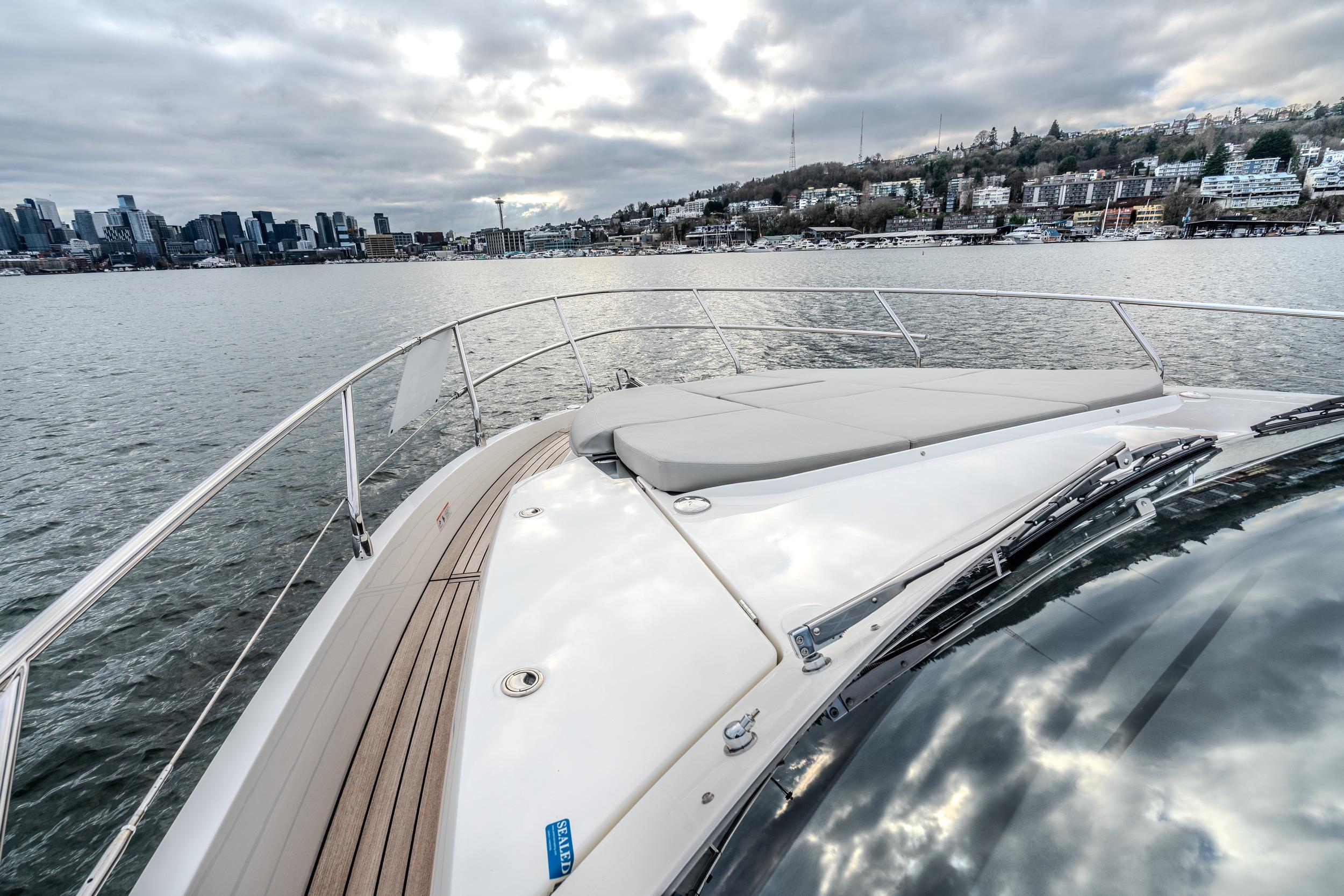 2026 Absolute 48 Coupe yacht cruising near city skyline under cloudy skies.