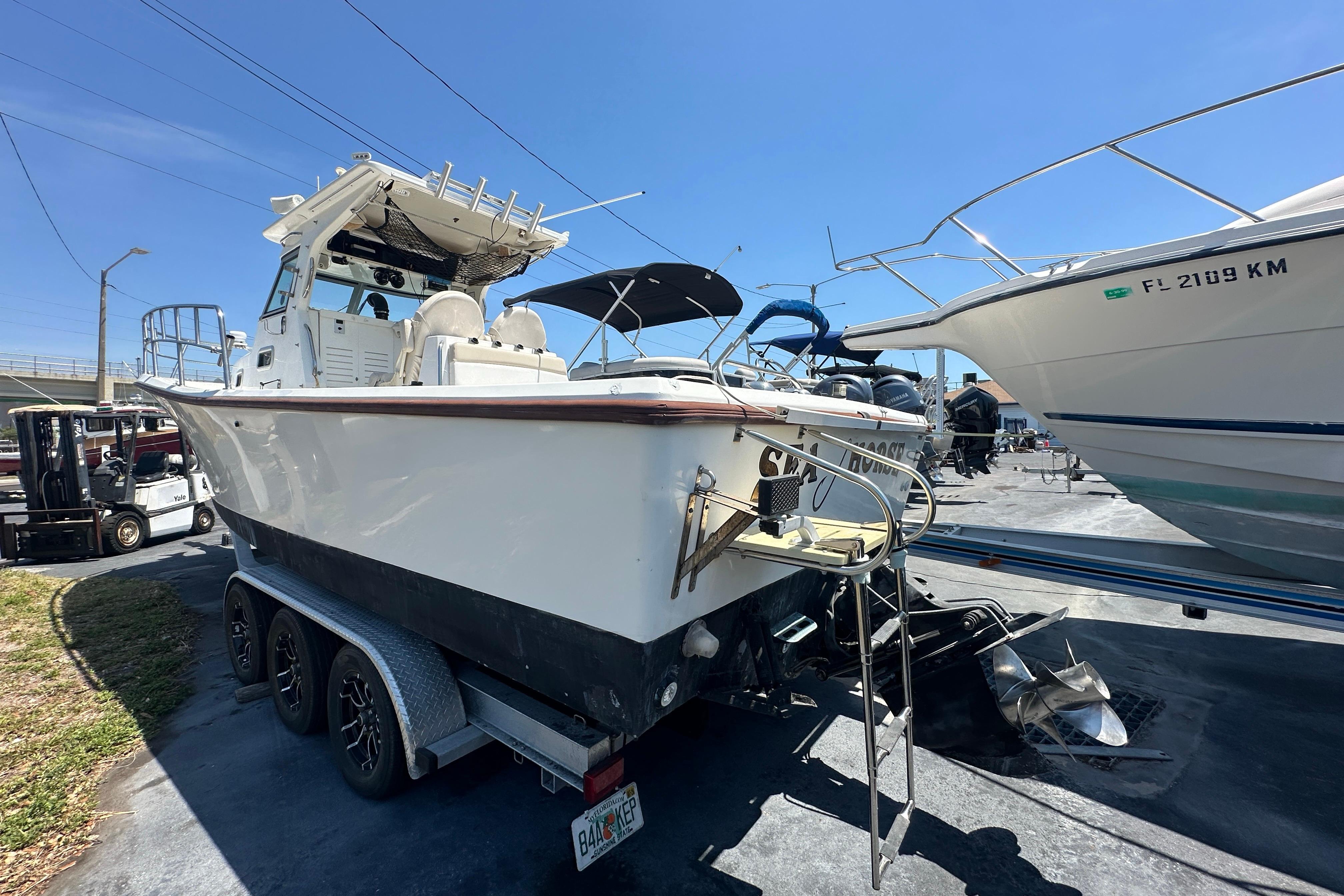 1998 True World Marine TE286 boat on trailer, parked outdoors under clear blue sky.
