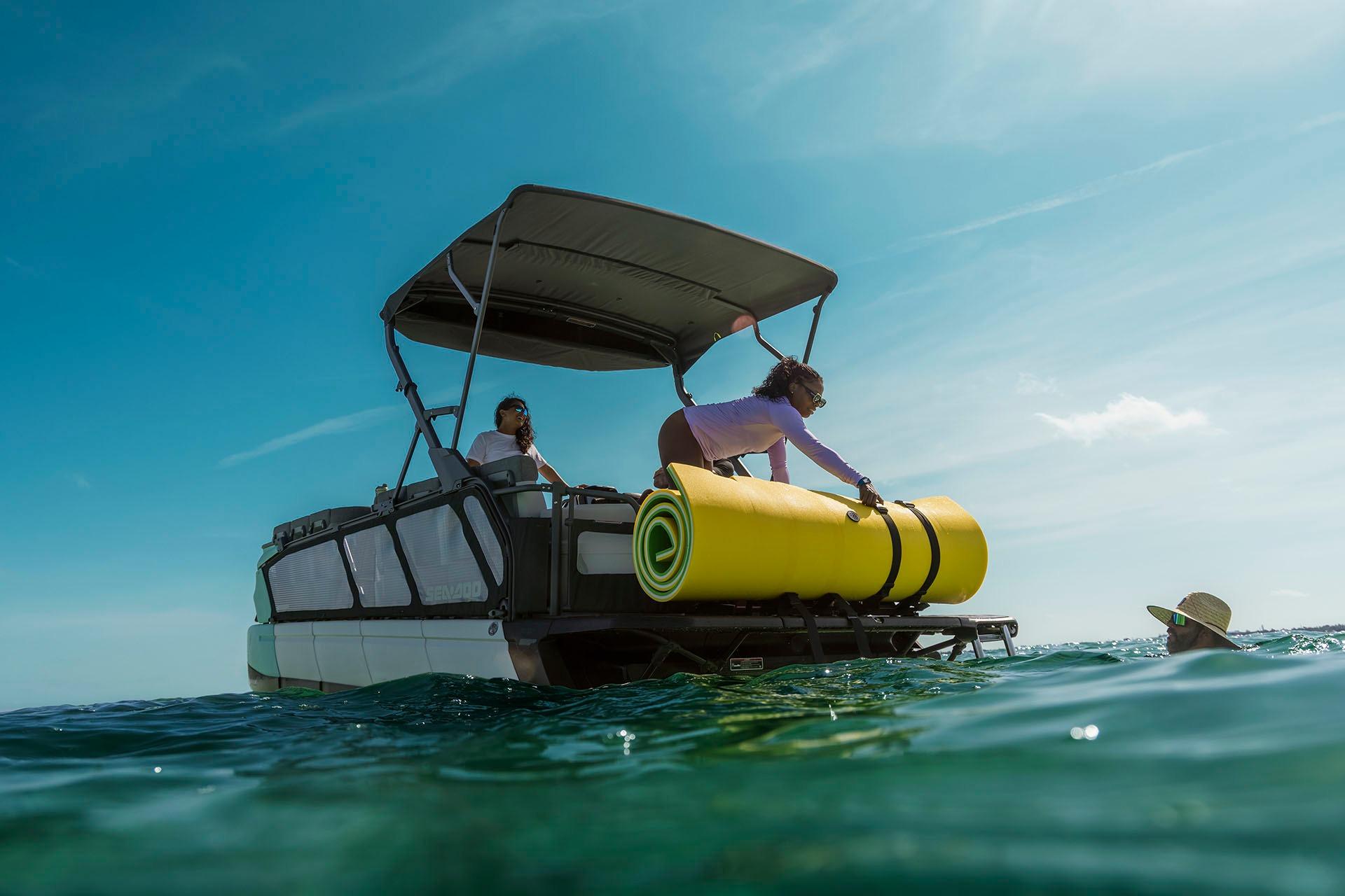 2026 Sea-Doo Switch Cruise 21 on water, people enjoying sunny day, yellow float onboard.