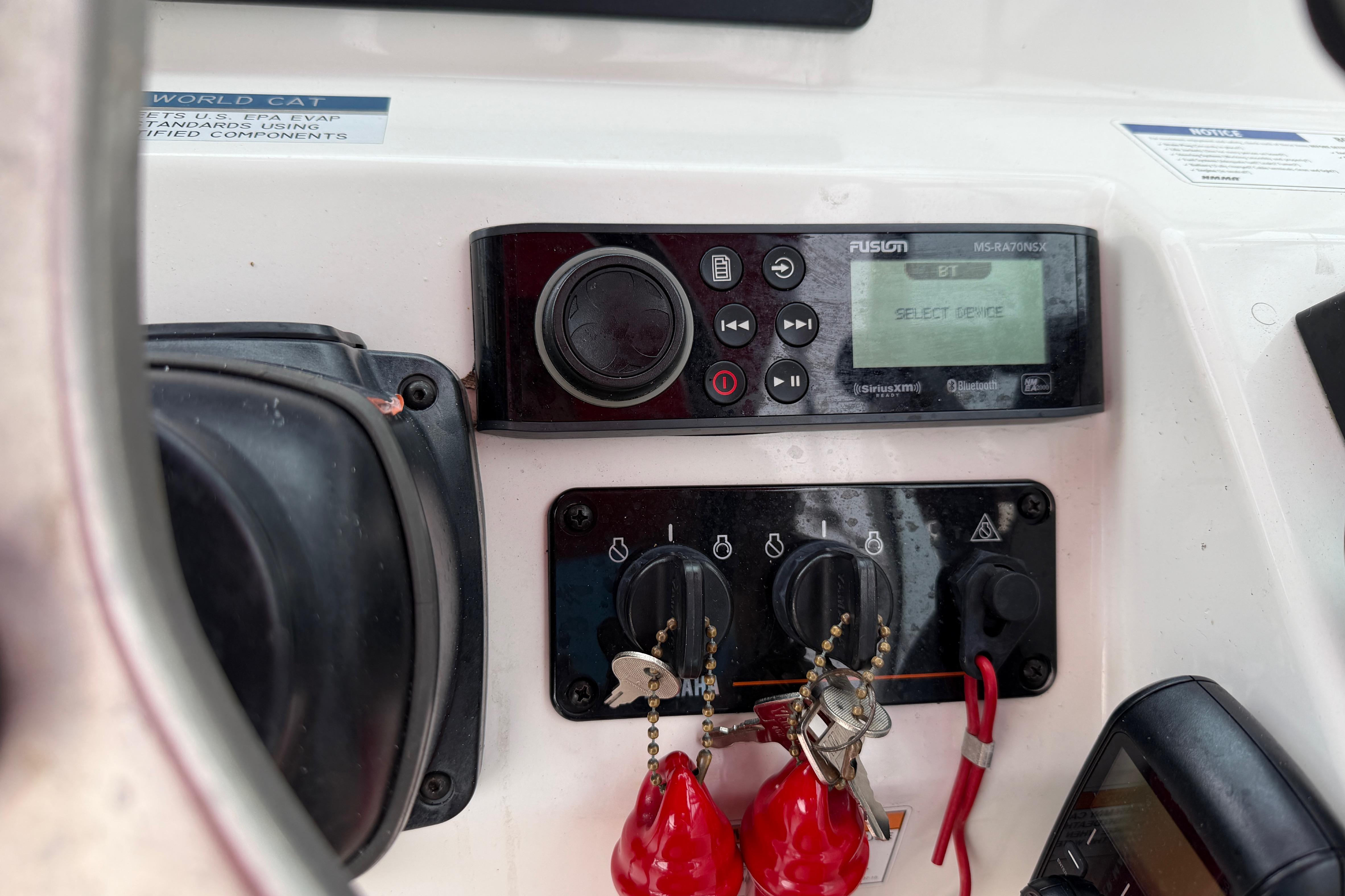 Control panel of a 2019 World Cat 230 DC boat with stereo system and keys.