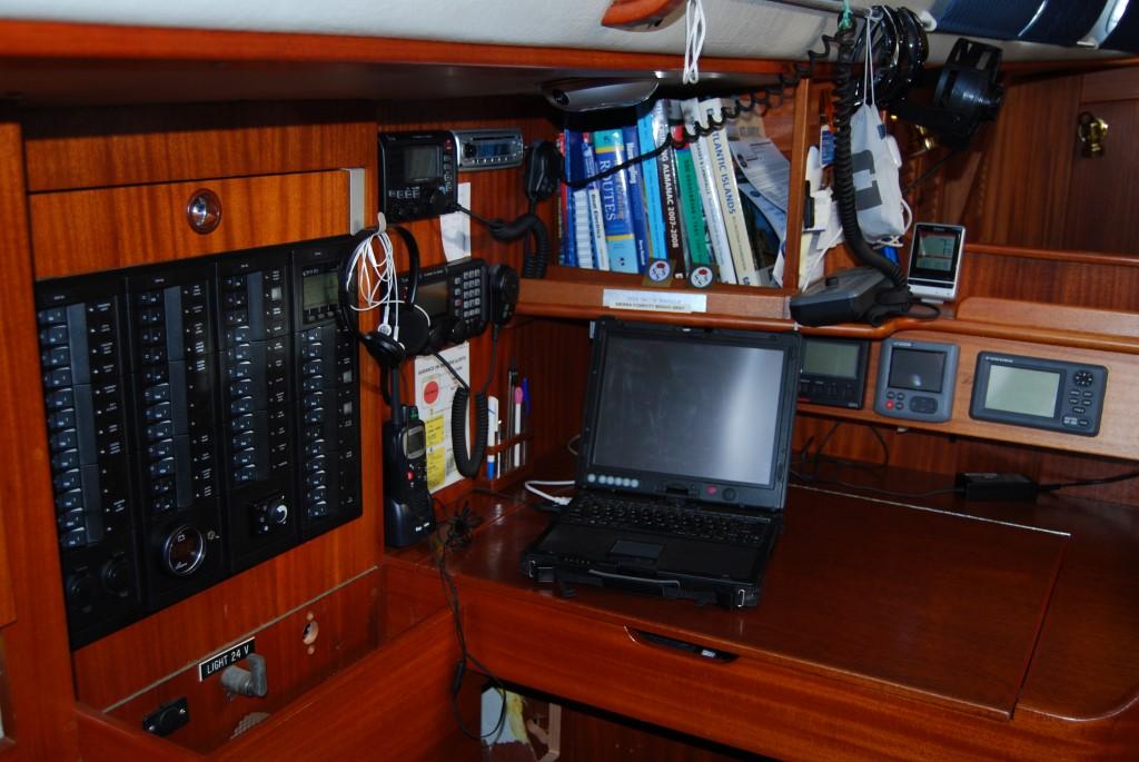 Navigation station inside a 1991 Hallberg-Rassy 45 yacht, featuring electronics and a laptop.