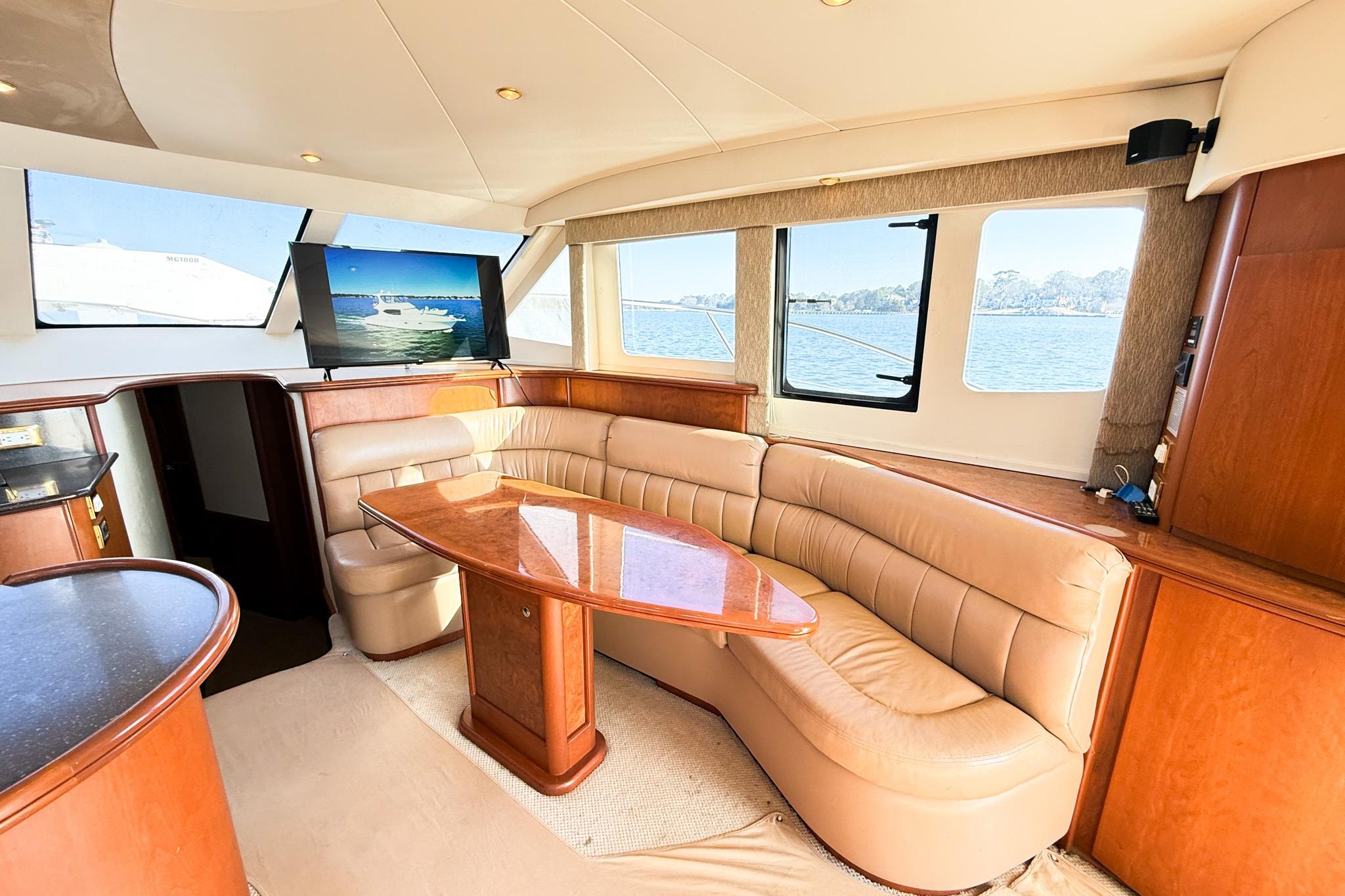 Luxurious interior of 2004 Silverton 48 Convertible yacht with leather seating and wooden table.