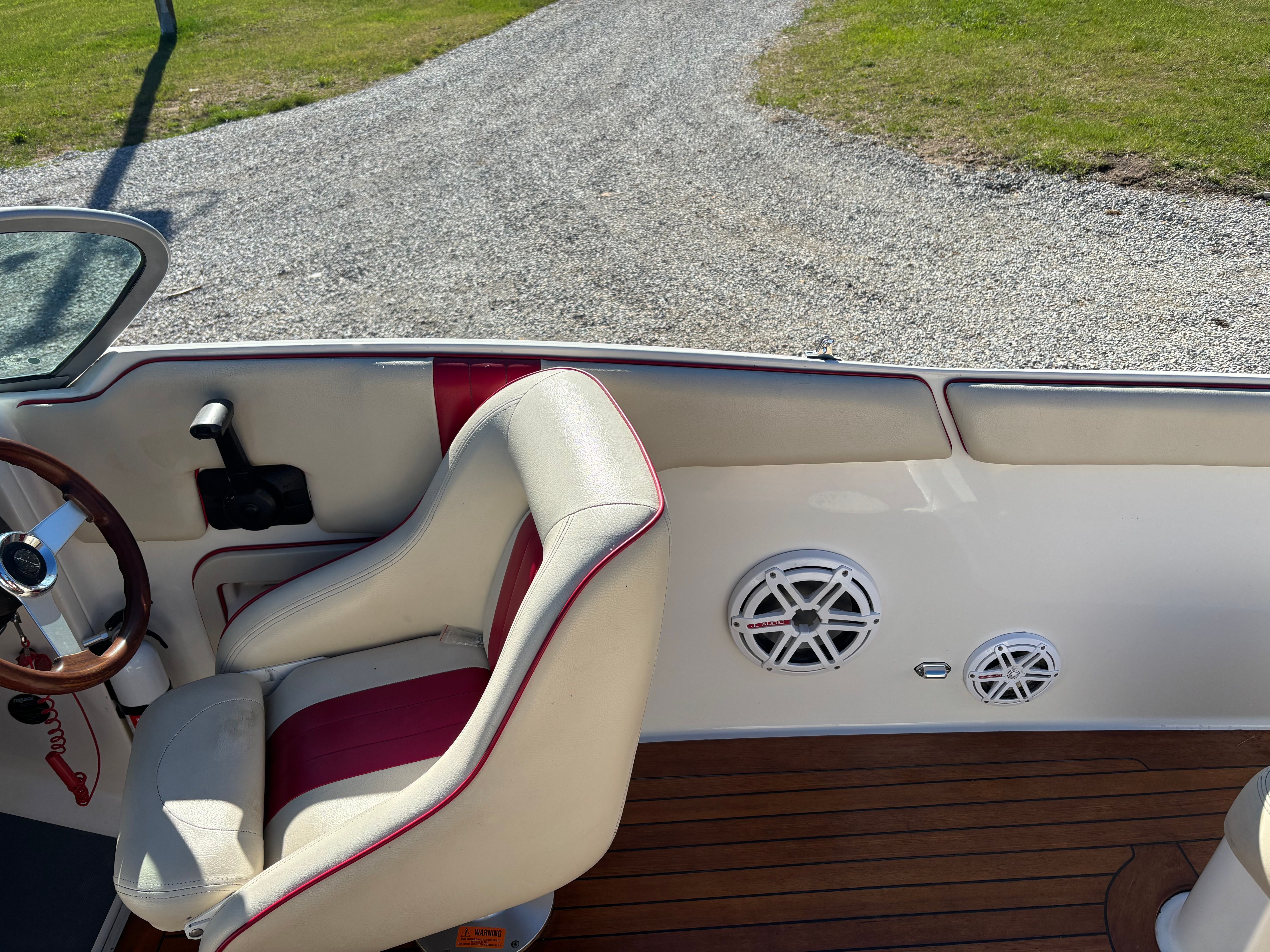 Interior view of a Chris-Craft Launch 22 boat with white and red seats and wooden flooring.