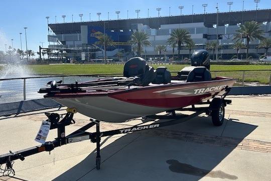 2026 Tracker Pro Team 175 boat on trailer, parked near a stadium with palm trees.