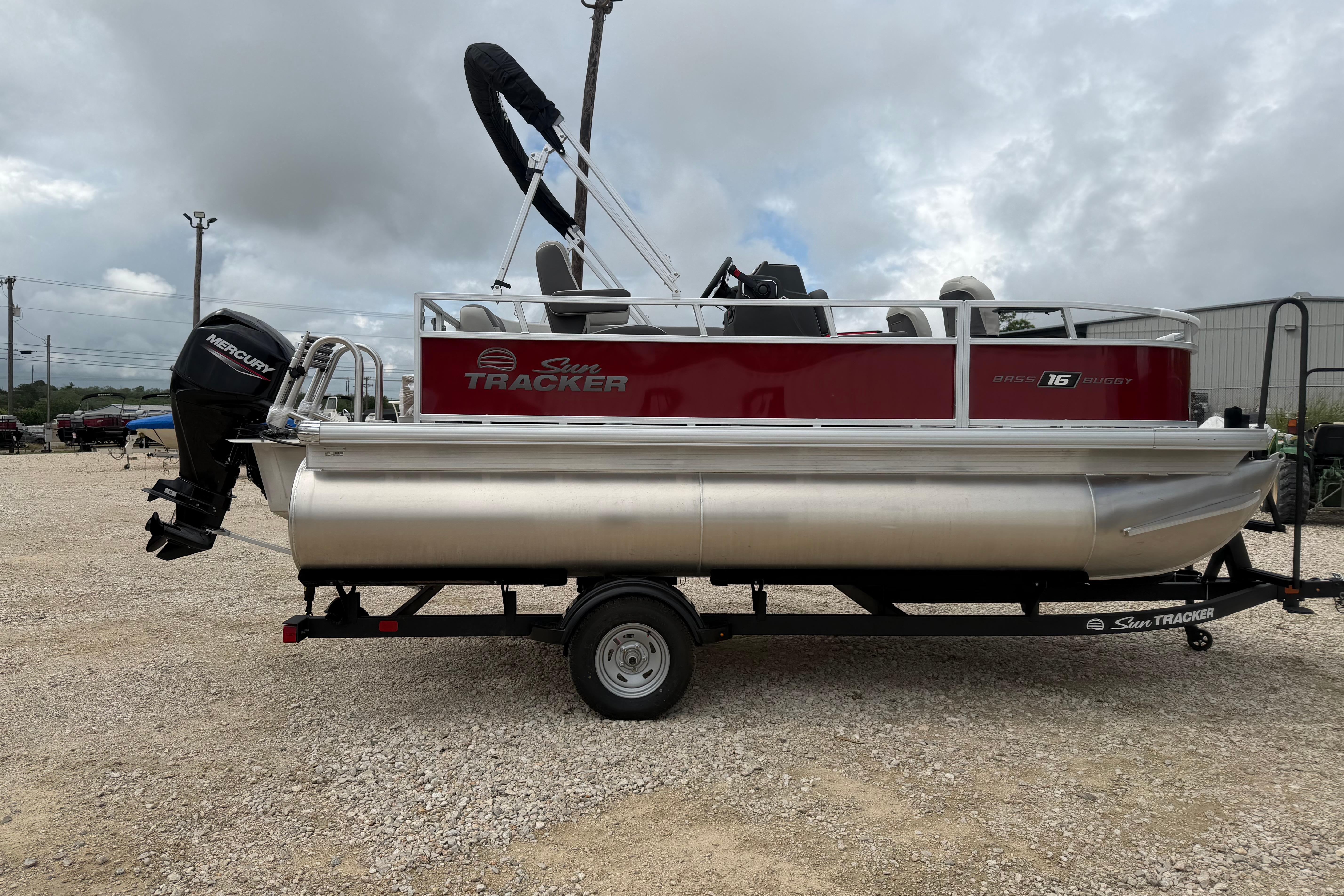 2026 Sun Tracker Bass Buggy 16 XL Select pontoon boat on trailer, outdoor setting.