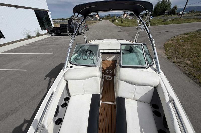 2004 MasterCraft XStar boat with white seating and wooden deck, parked outdoors.