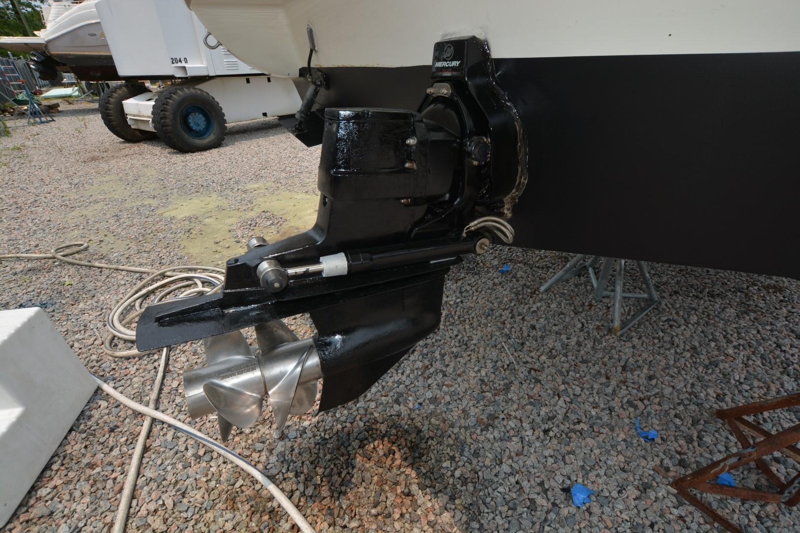 1999 Rinker 270 Fiesta Vee boat propeller and drive system on gravel surface.