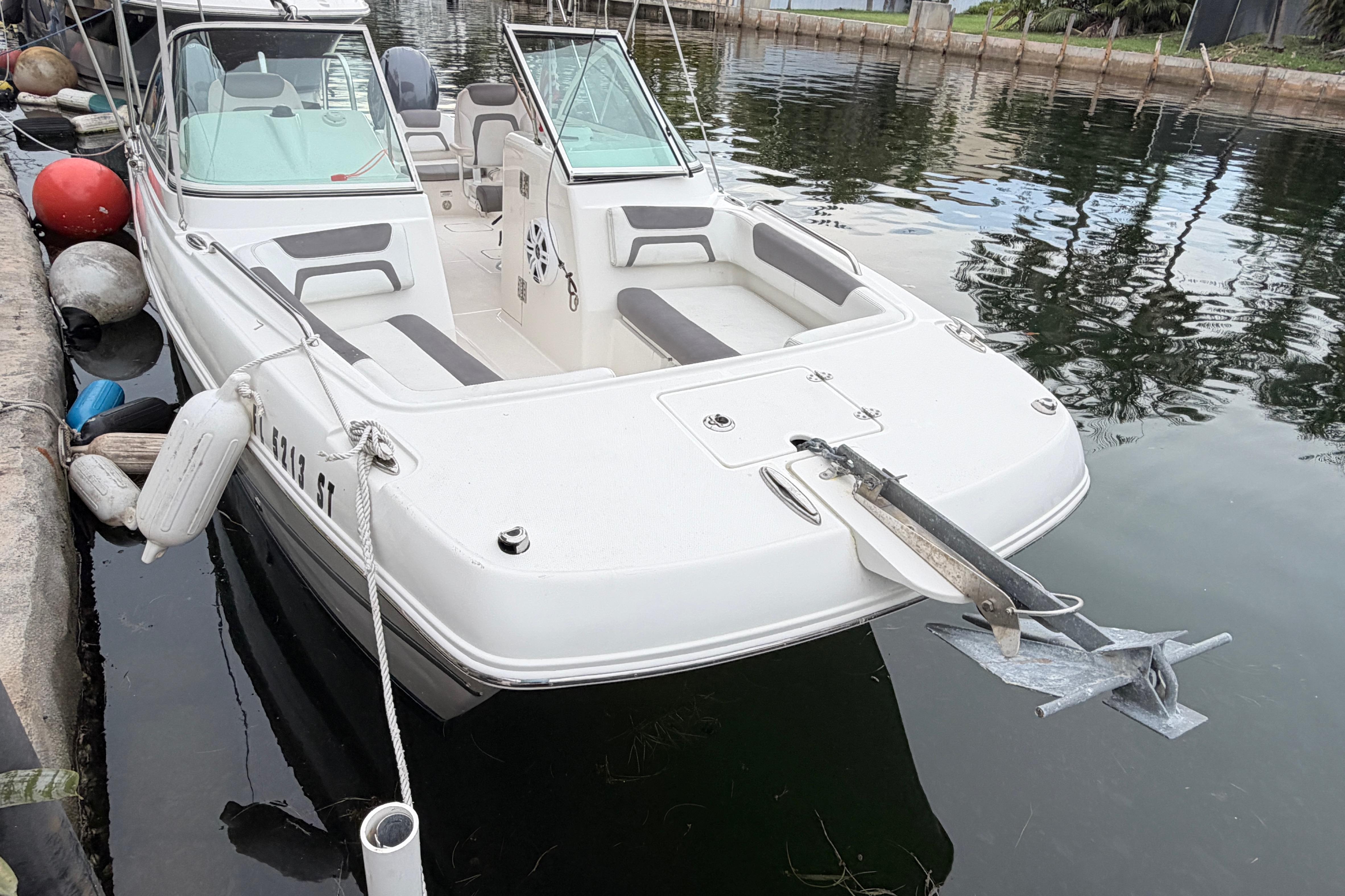 2019 World Cat 230 DC boat docked in calm waters, featuring spacious seating and anchor.