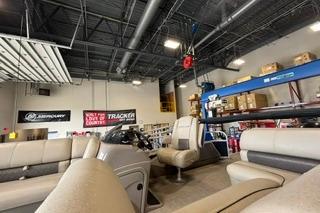 2022 Sun Tracker Fishin' Barge 22 DLX in a showroom with seating and equipment.