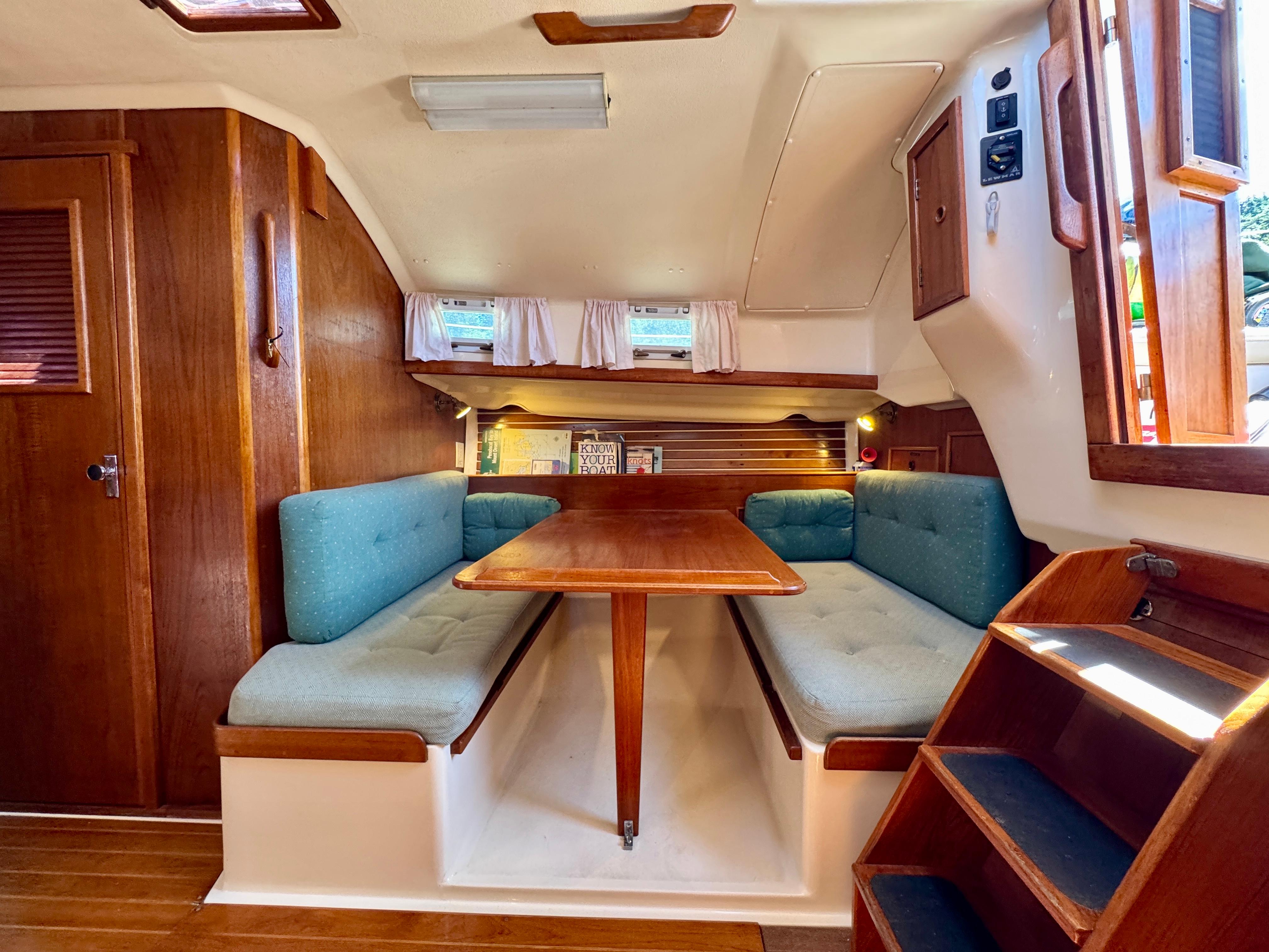 Cozy interior of 1989 Nonsuch 30 Ultra sailboat with wooden dining area.
